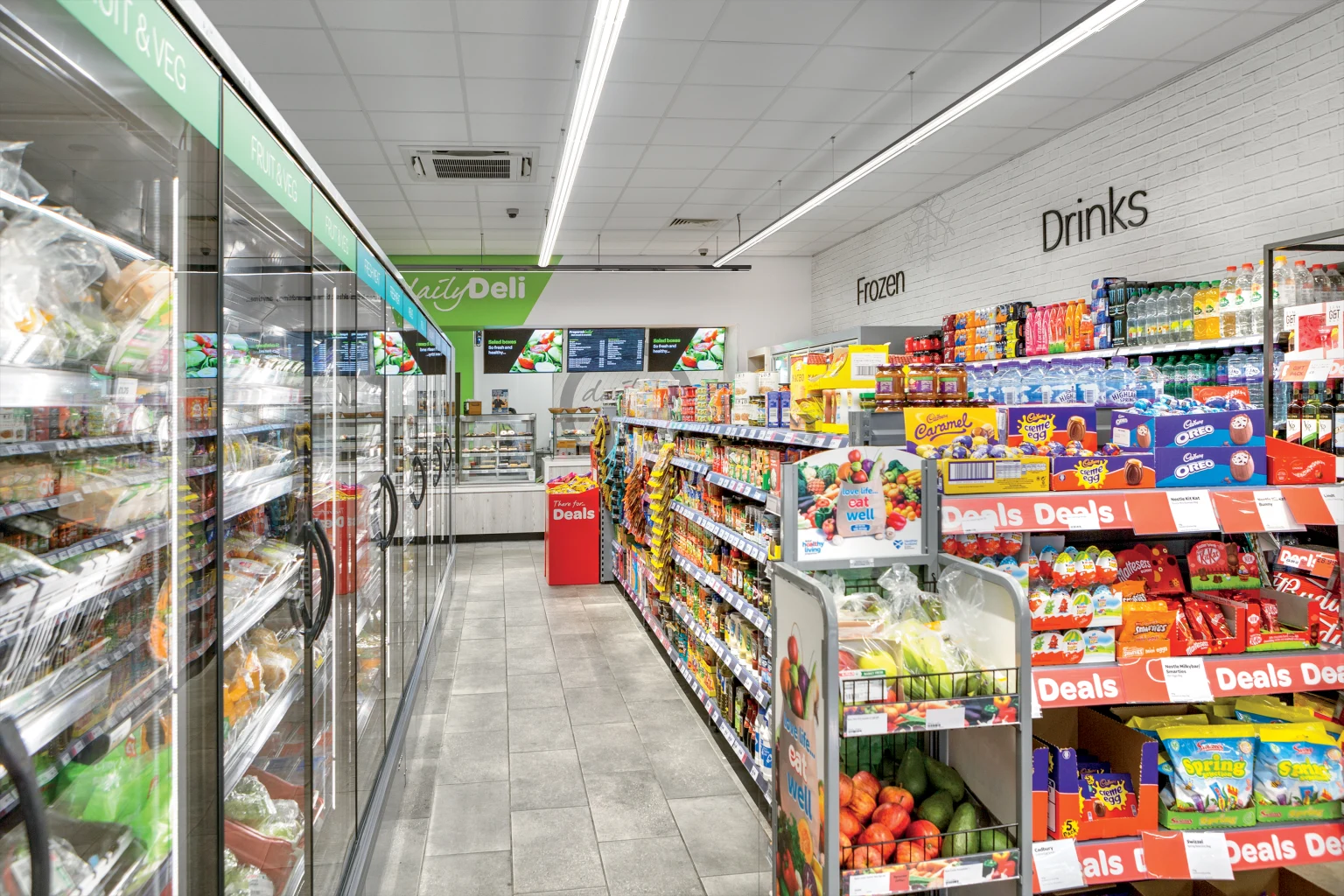 A convenience retail store with assorted food items, lit by Arrowslim battens