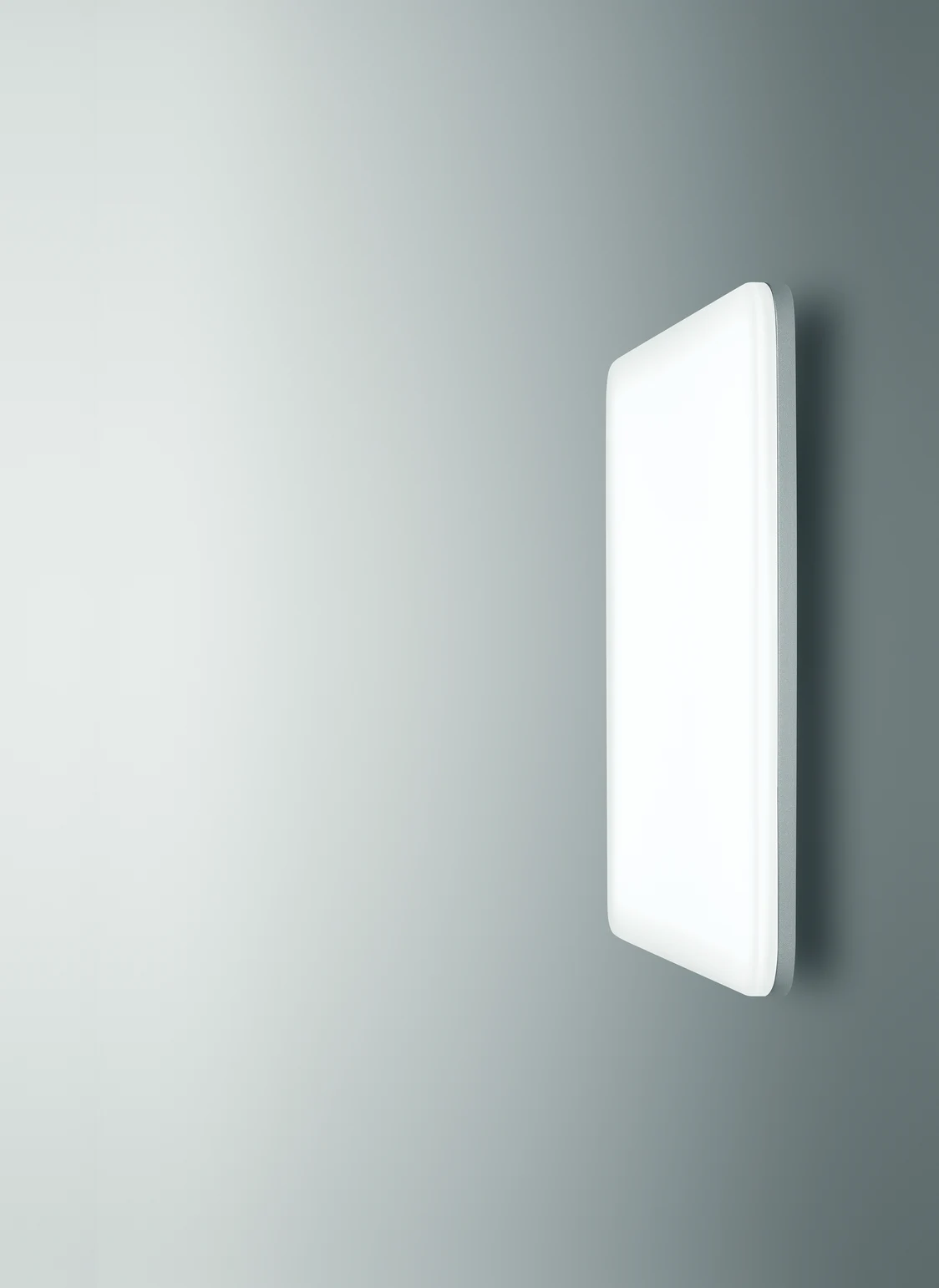 L'apparecchio illuminotecnico CAELA di forma quadrata è appeso a una parete grigia e semplice. 