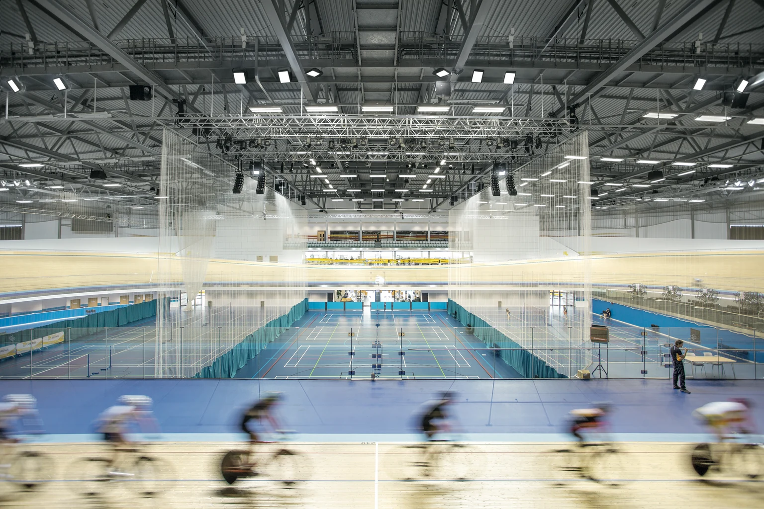 Derby Arena Velopark con corridori in pista e sport della racchetta indoor al centro