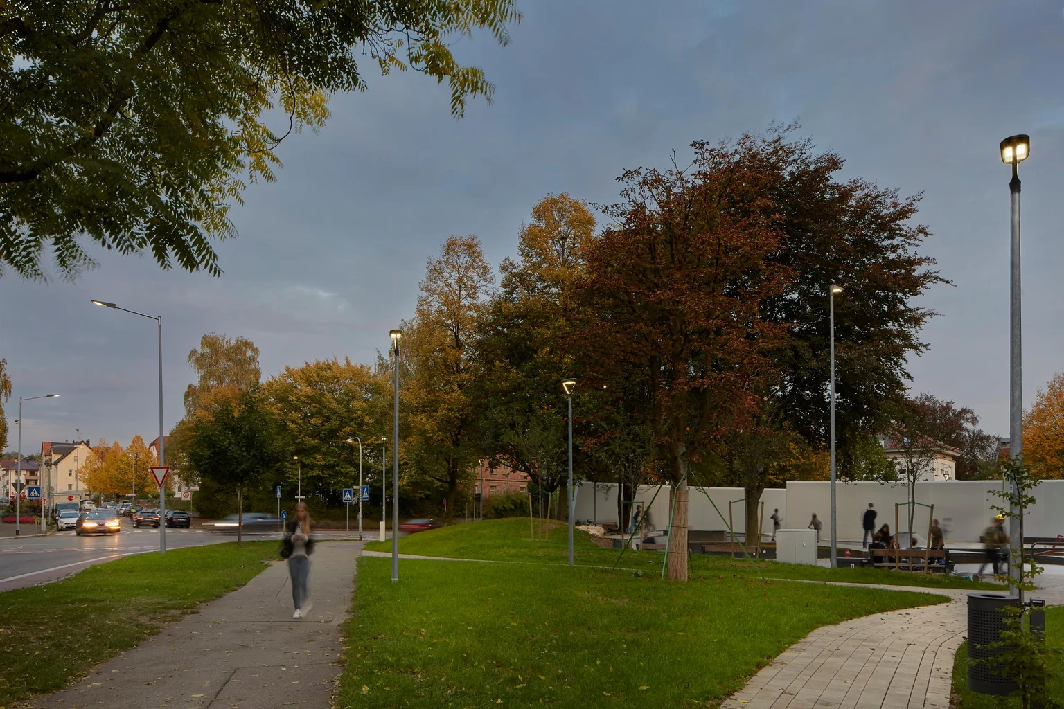Een pad en groenstrook naast een straat wordt gelijkmatig verlicht, waardoor het na zonsondergang aangenaam is voor voetgangers en fietsers.