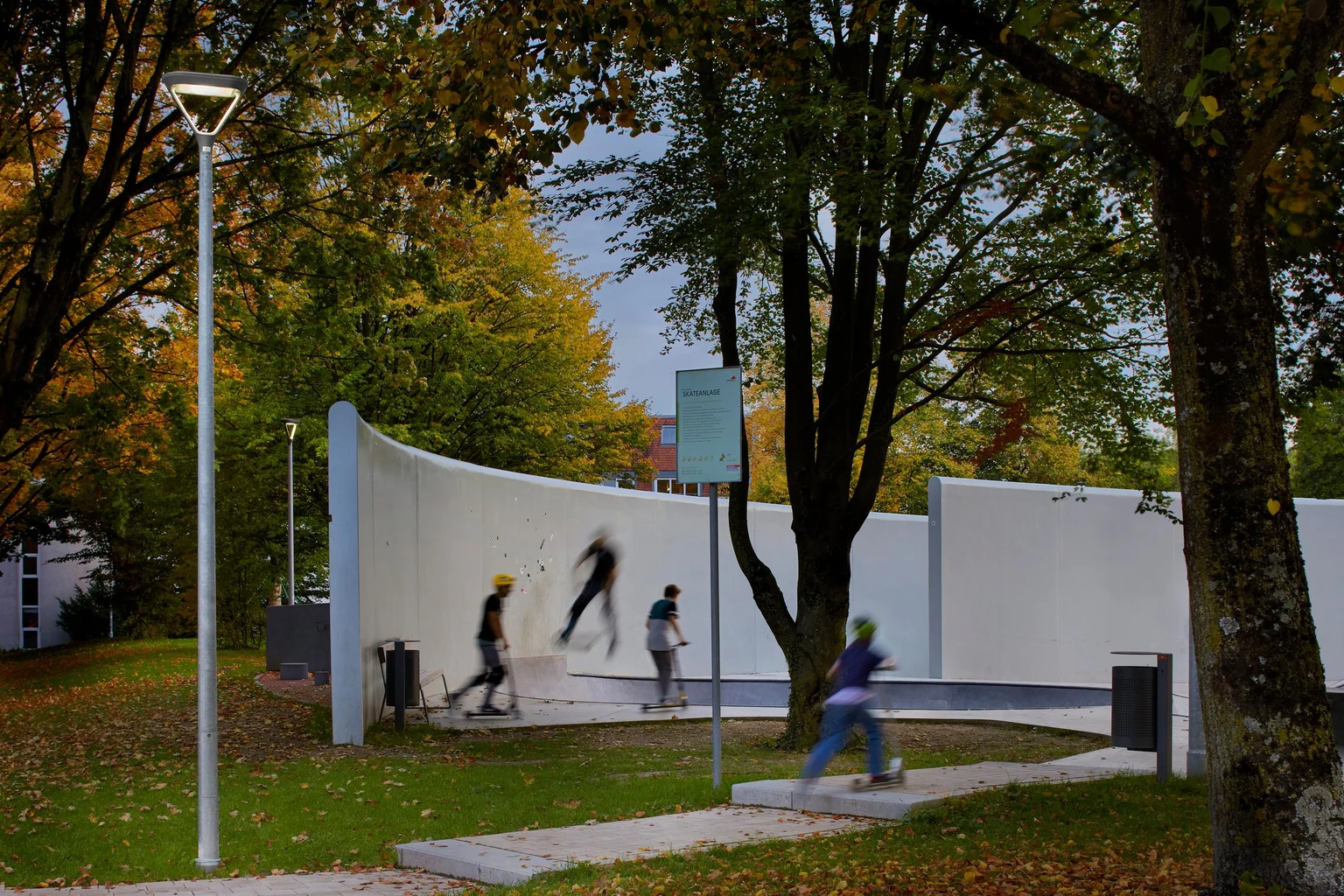 Een skatepark omgeven door bomen is goed verlicht, waardoor het activiteitengebied wordt benadrukt en de veiligheid voor gebruikers 's avonds wordt verbeterd.