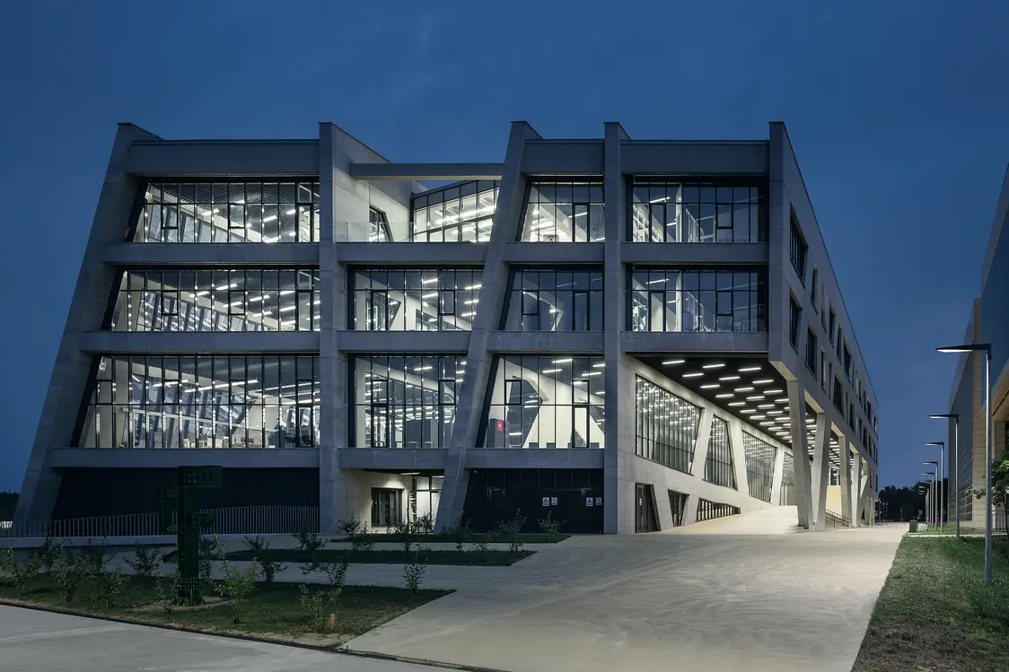 Eine Gesamtansicht des Gebäudes bei Nacht, das durch die Beleuchtung von innen und außen hervorgehoben wird. Die Kombination aus LED-Lichtlösungen und der Glas-Beton-Architektur schafft ein beeindruckendes Erscheinungsbild.