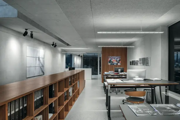 Ein Büro mit mehreren modernen Arbeitsplätzen und einem langen, hölzernen Sideboard, komplett mit passenden Bürobeleuchtungen