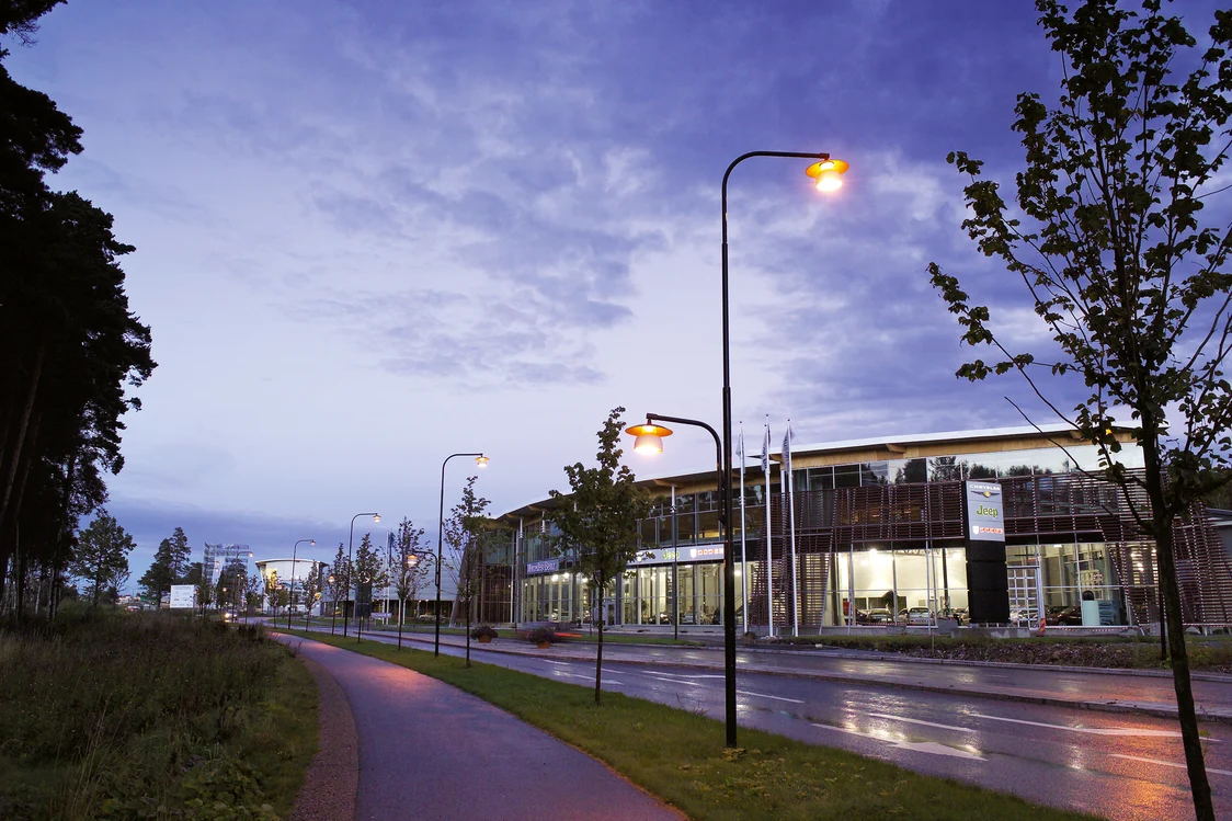 Illuminated street at dusk with modern streetlights and buildings in the background, Zumtobel