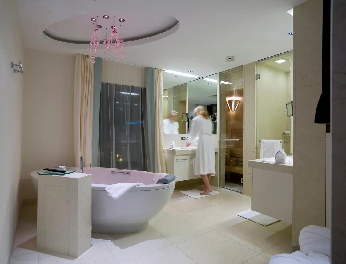 Une salle de bain luxueuse avec une baignoire sur pied et des touches déco élégantes. De grands miroirs et des parois vitrées créent une atmosphère lumineuse et moderne.