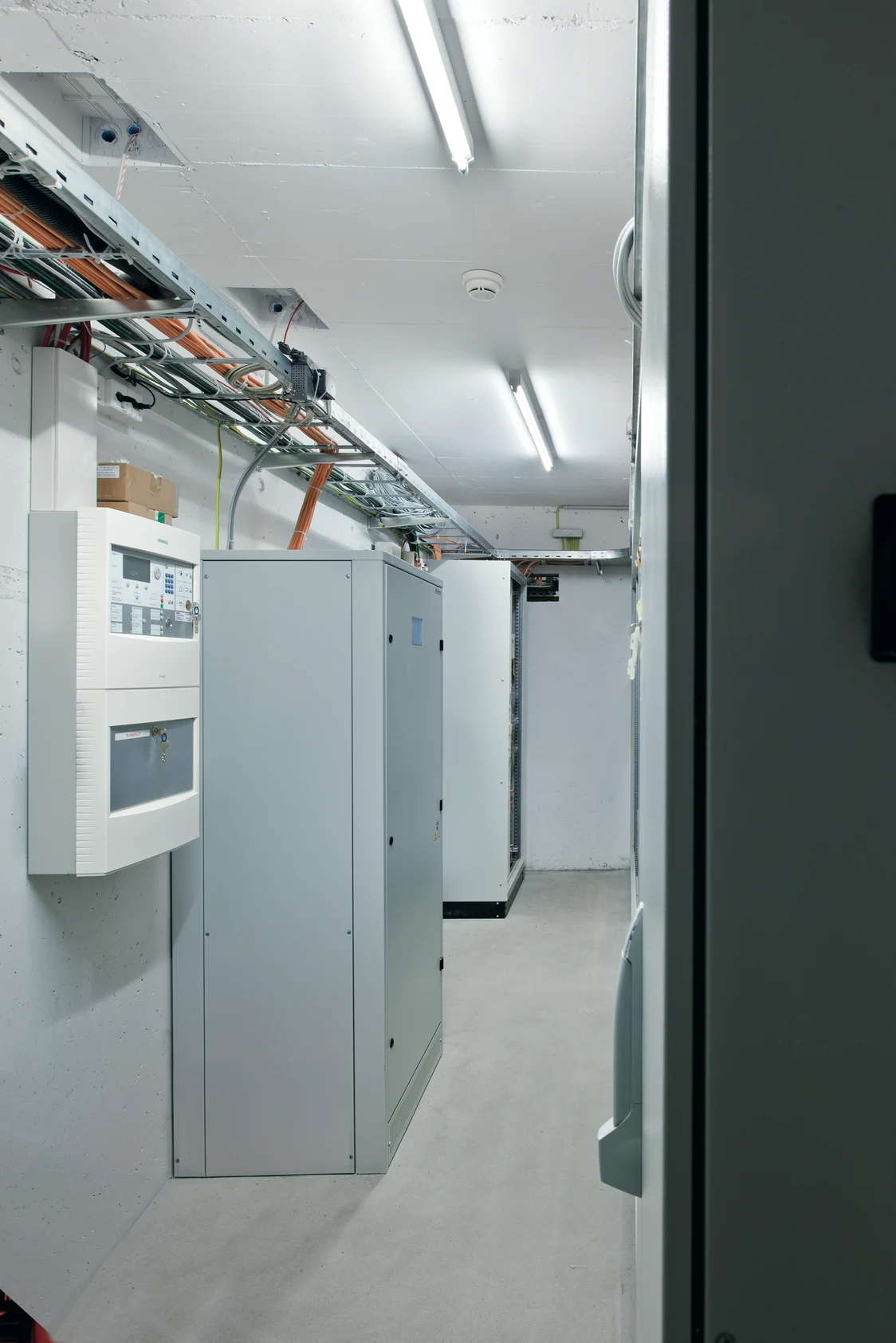 The ONLITE central CPS lighting system in a technical room with distribution boxes and cables on the ceiling and walls.