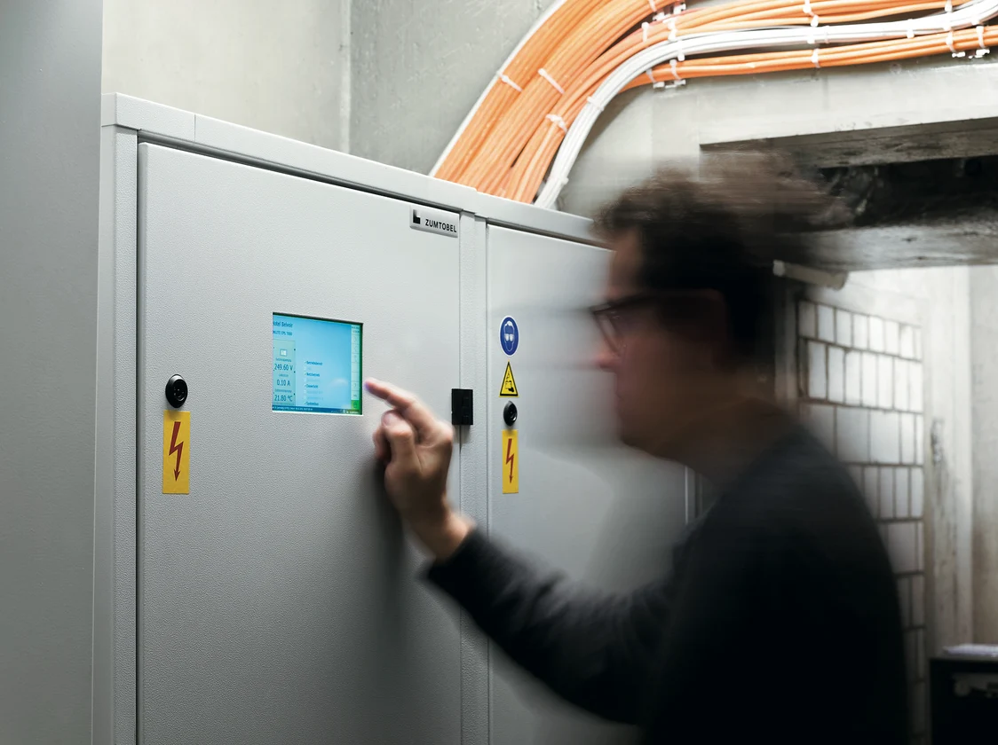 Das ONLITE central CPS ist ein graues Schaltschrankgehäuse mit einem kleinen Display zur Steuerung und Überwachung von Notbeleuchtungssystemen.