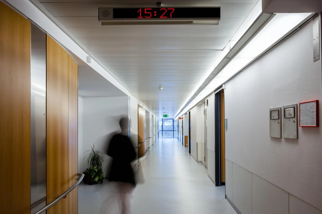 Moderner Krankenhausbereich mit Holzschränken, Waschbecken und grün beleuchteter Decke im LKH Bruck an der Mur.