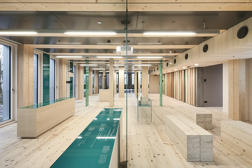 Heldere, moderne ruimte met veel daglicht door grote ramen, gecombineerd met lineaire plafondverlichting als verlichtingsoplossing; de inrichting van licht hout en glas zorgt voor een open, vriendelijke sfeer.