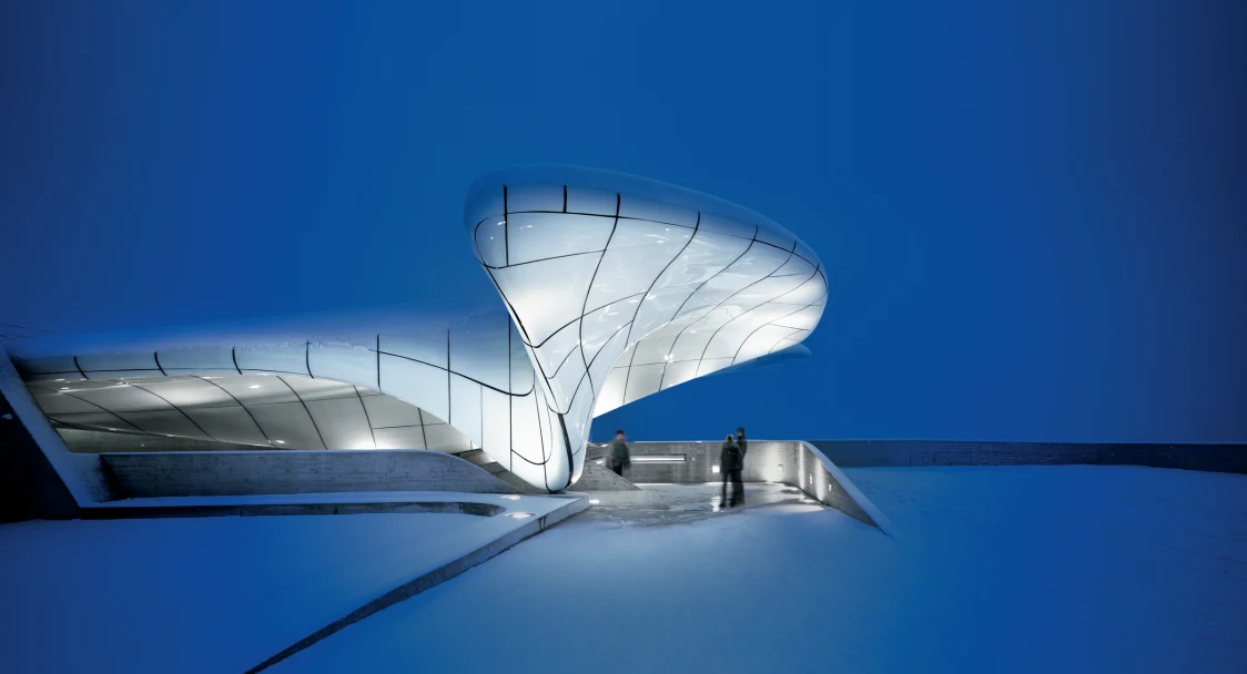 Een modern glazen gebouw tegen een diepblauwe hemel.