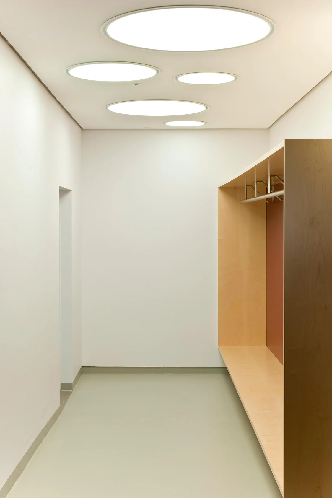 ONDARIA II luminaires ensure uniform, glare-free lighting in a modern hallway with light-coloured wooden shelving and white walls.