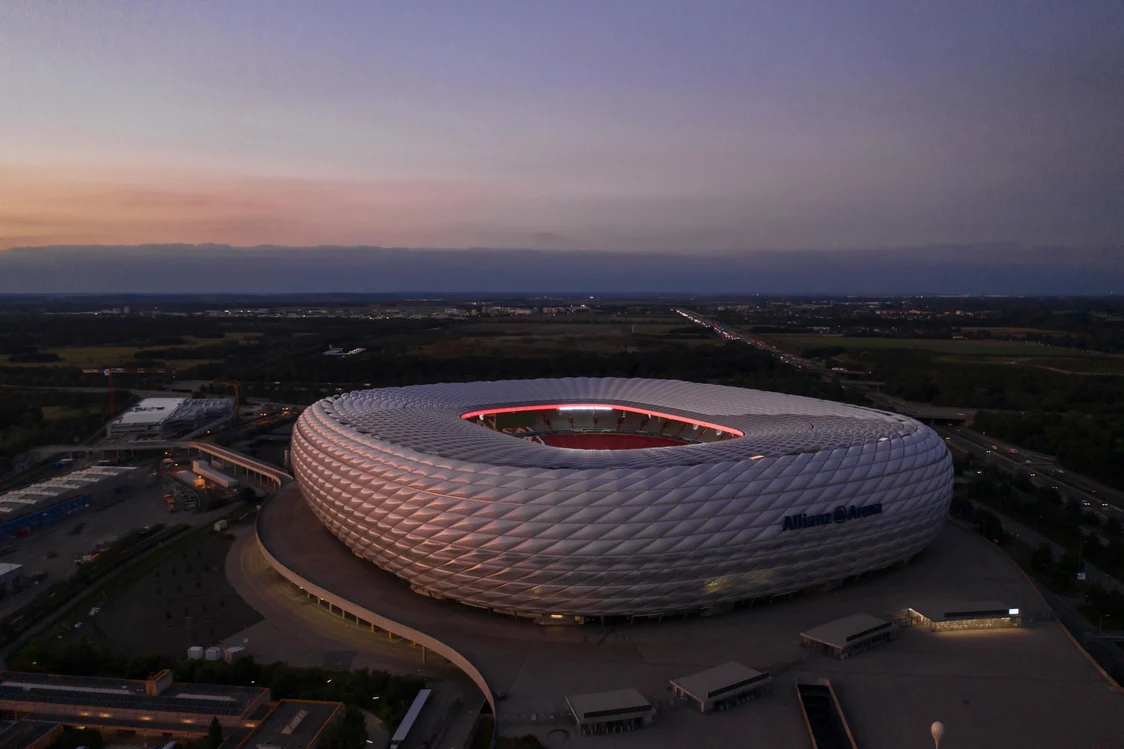 Curved metal facades of the Guggenheim Museum in Bilbao at dusk, artistically illuminated against a cloudy sky.
