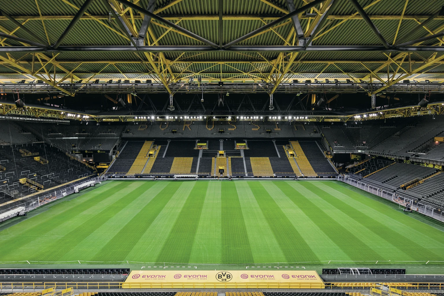 Binnenaanzicht van Signal Iduna Park, met het felgroene voetbalveld met perfect gemaaide strepen. De iconische gele staalconstructies en de tribunes zorgen in dit opvallende en moderne stadion voor een gezellige sfeer.