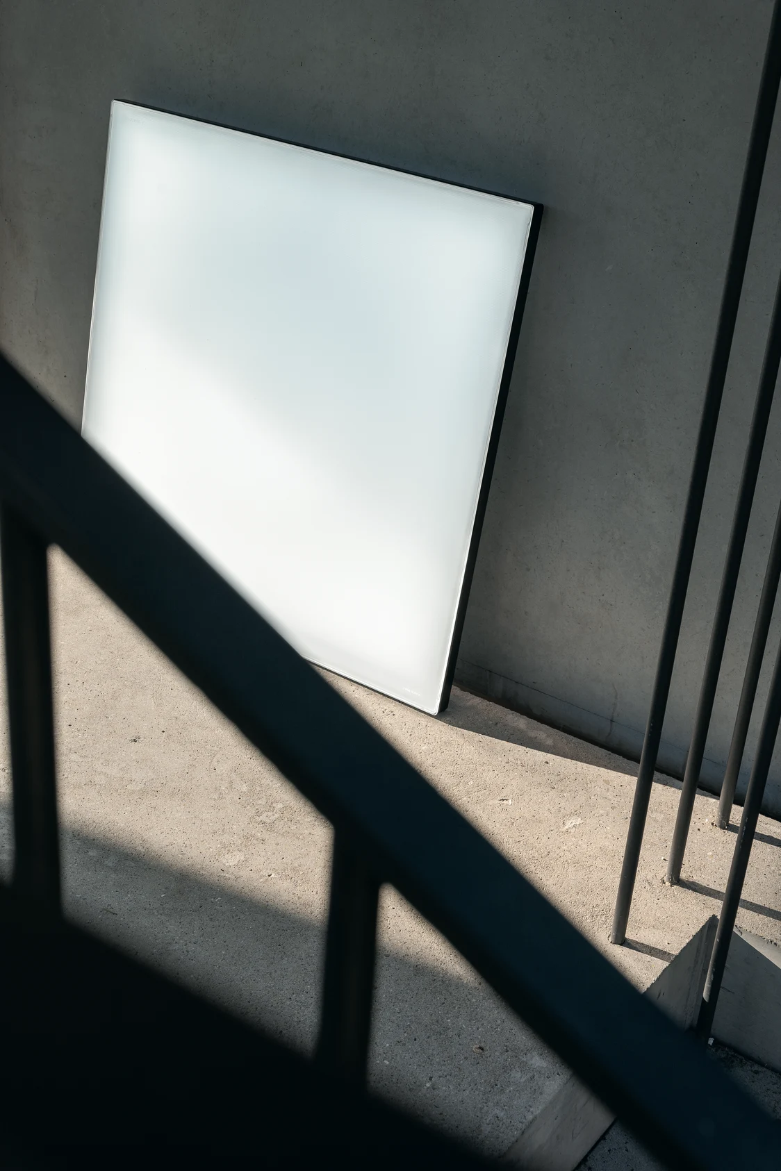 Light Fields III LED panel leans against a concrete wall on a landing, reflecting diffused daylight in a modern setting.