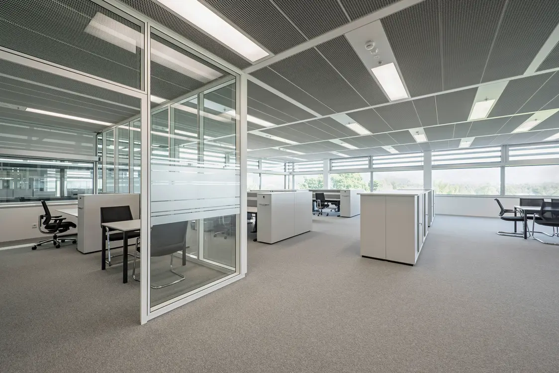 Bureau paysager baigné de lumière naturelle, avec un éclairage LED uniforme et des postes de travail ouverts favorisant la collaboration en équipe.