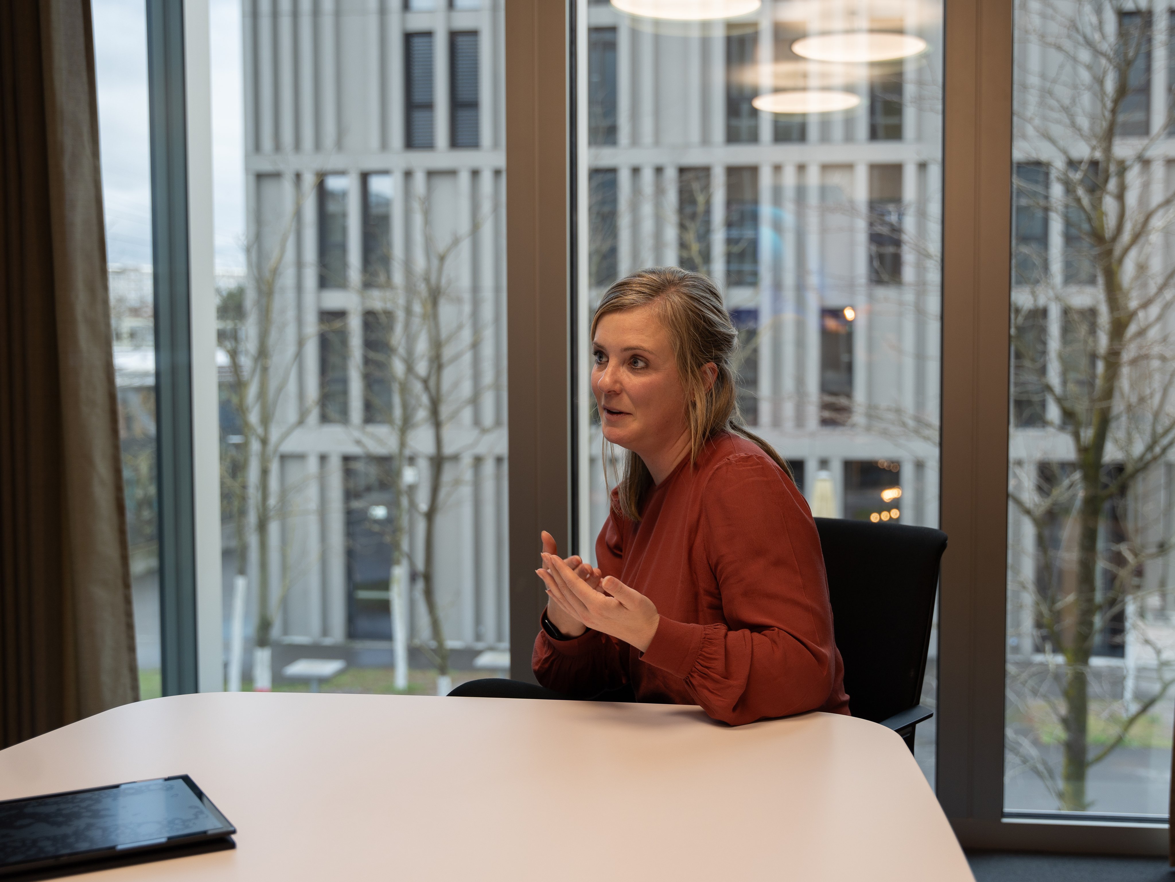 Sandra Schwander durante l’intervista: gesticola e guarda il redattore. Sullo sfondo, dalle grandi finestre, appaiono la stazione di Wankdorf e i binari. La conversazione ha luogo nella sede centrale delle FFS. 