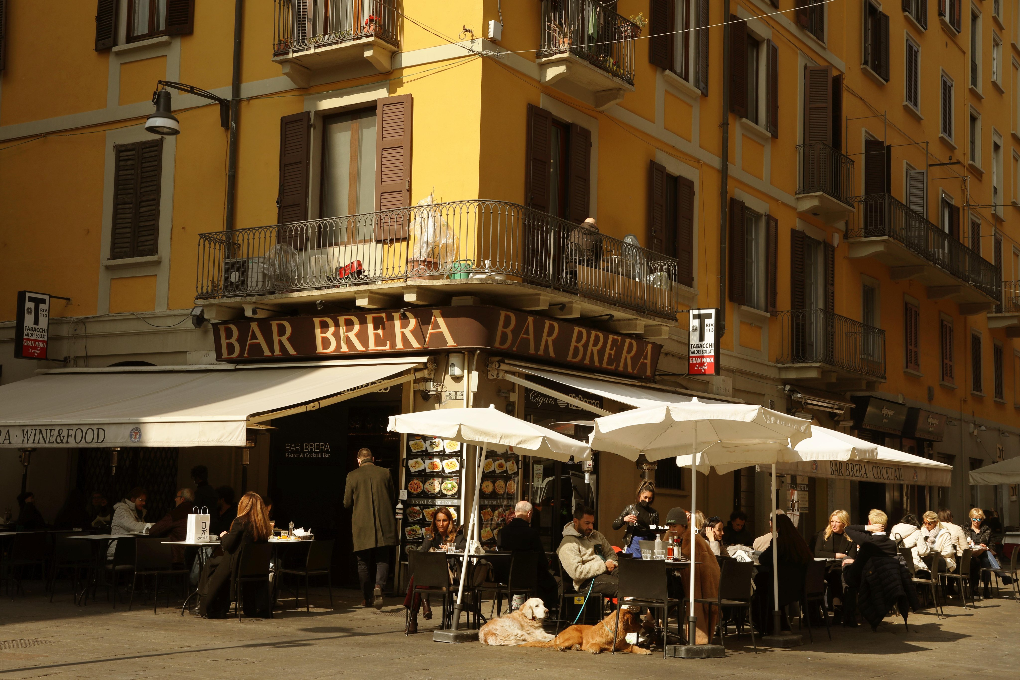 Strassenecke mit einer Bar, die im Freien Tische, Stühle und Sonnenschirme aufgestellt hat.