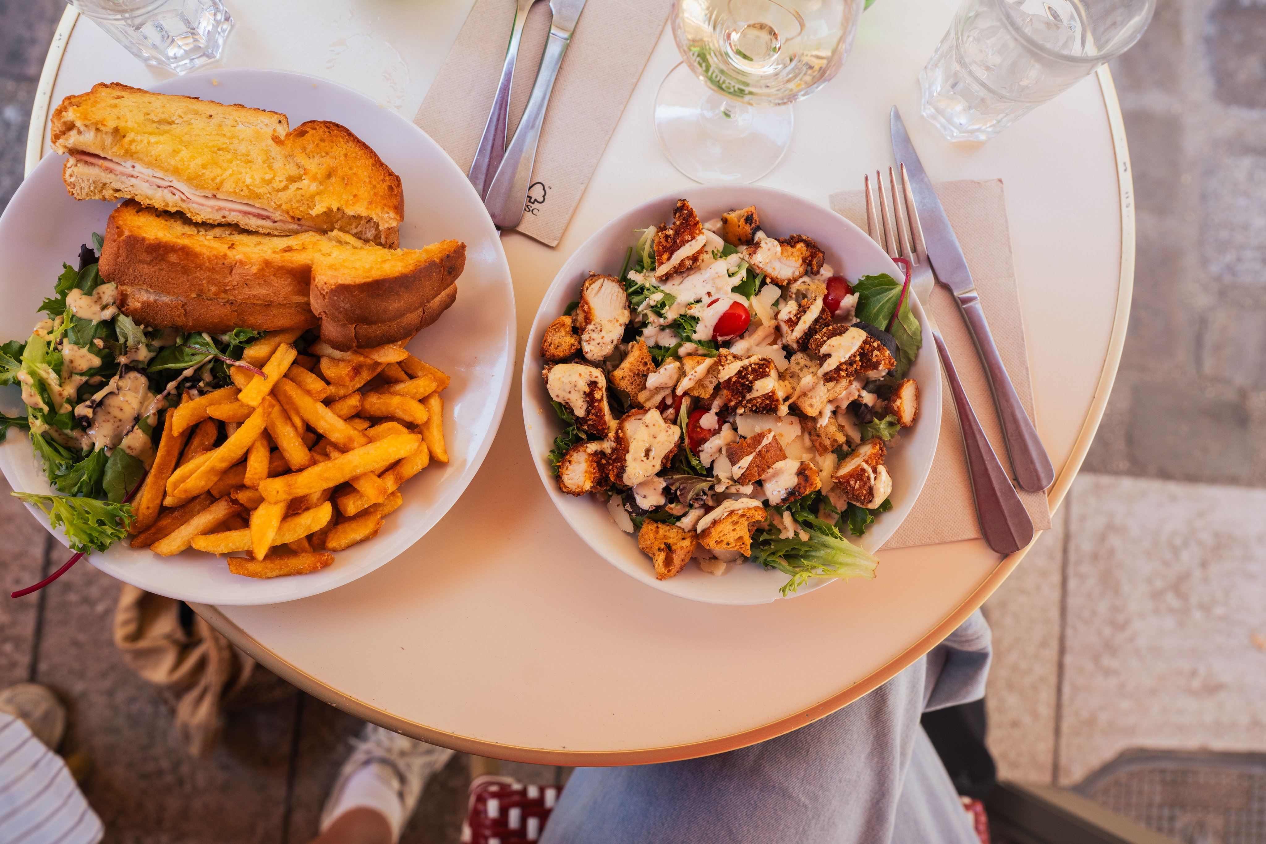 Ein aufgeschnittenes Croque Monsieur und ein knackiger Caesar-Salat stehen auf einem Tisch.