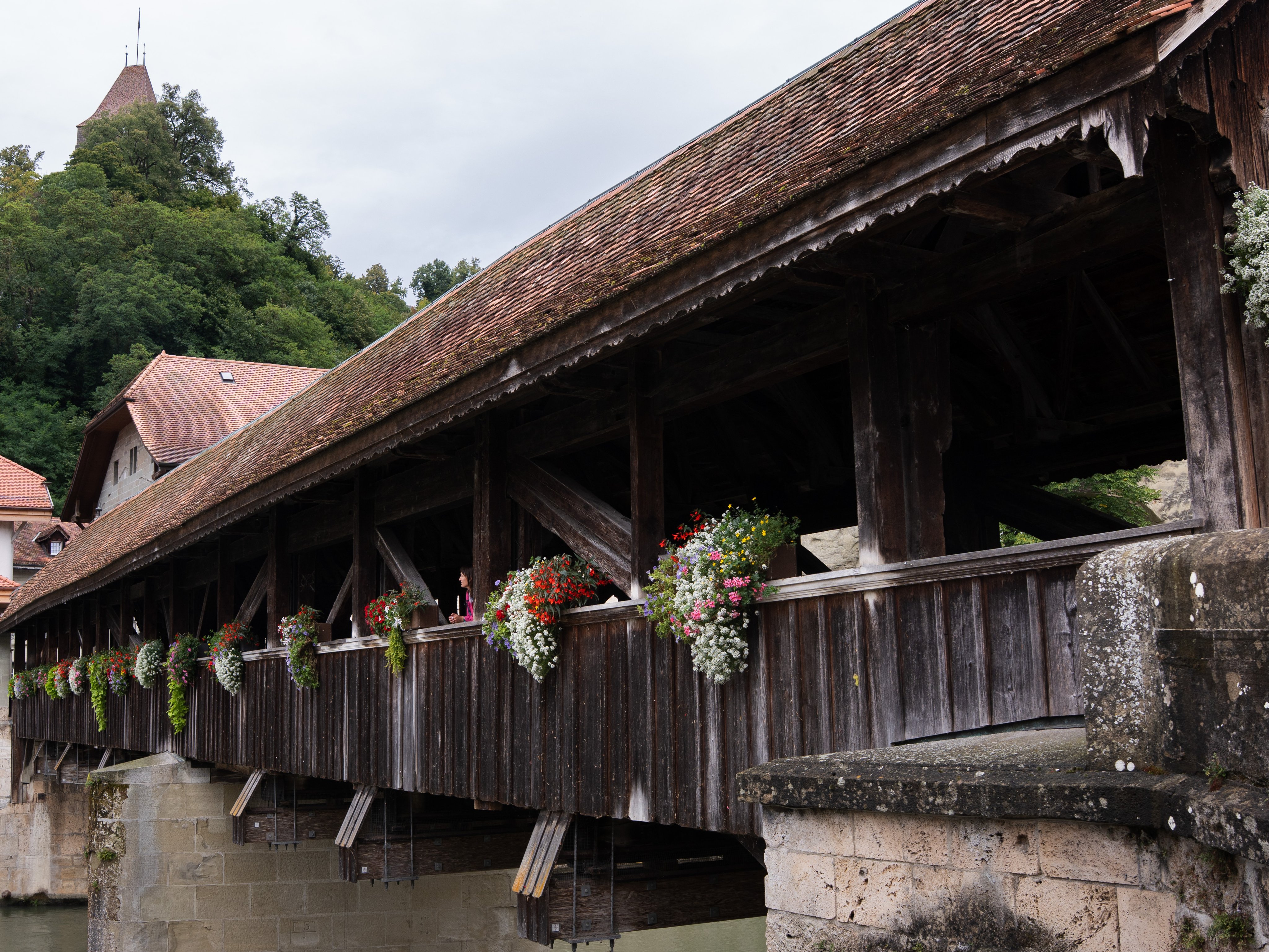 Eine Brücke aus Holz mit einem Dach und mit Blumendekoration.