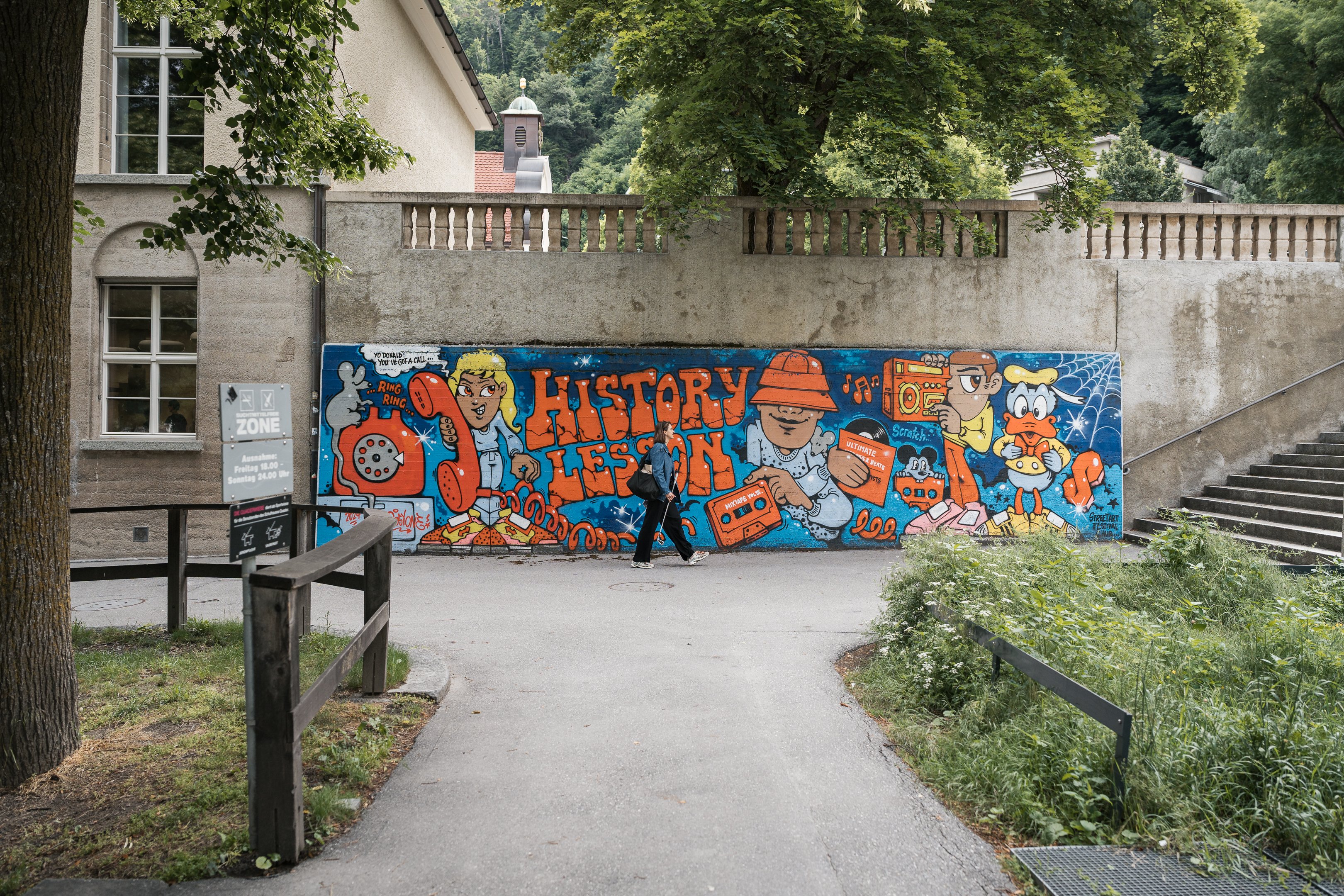Frau läuft an einer bunten Grafittiwand vorbei.
