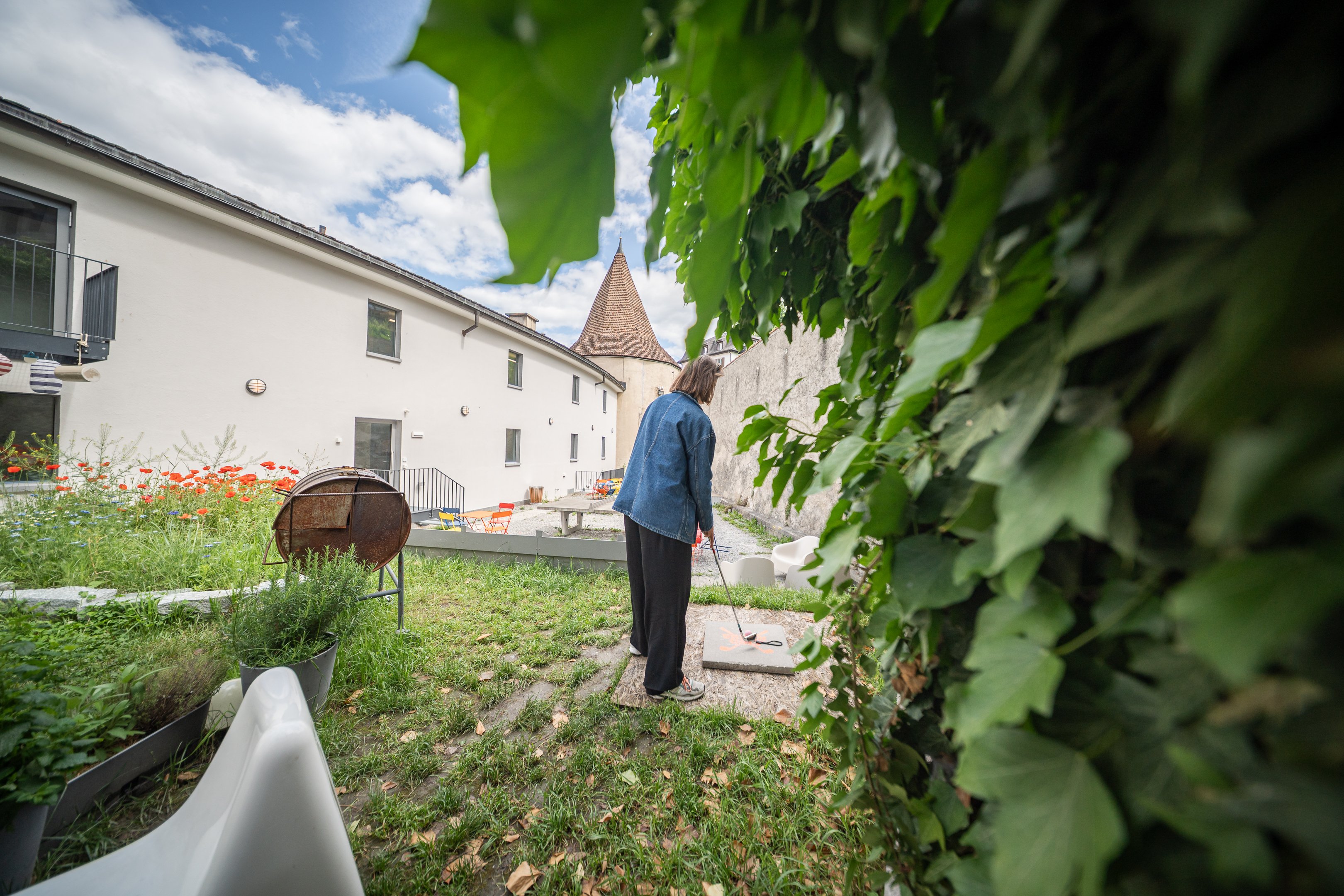 Frau in einem Innenhof hält Golfschläger in der Hand.