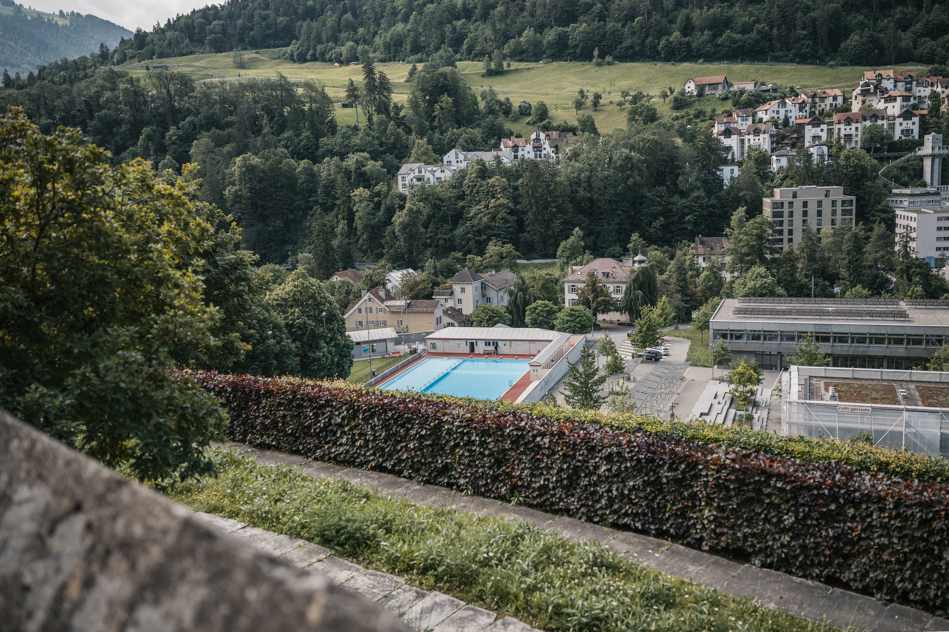 Aussicht auf Freibad Sand in Chur, viel Wiese und Bäume sichtbar daneben.
