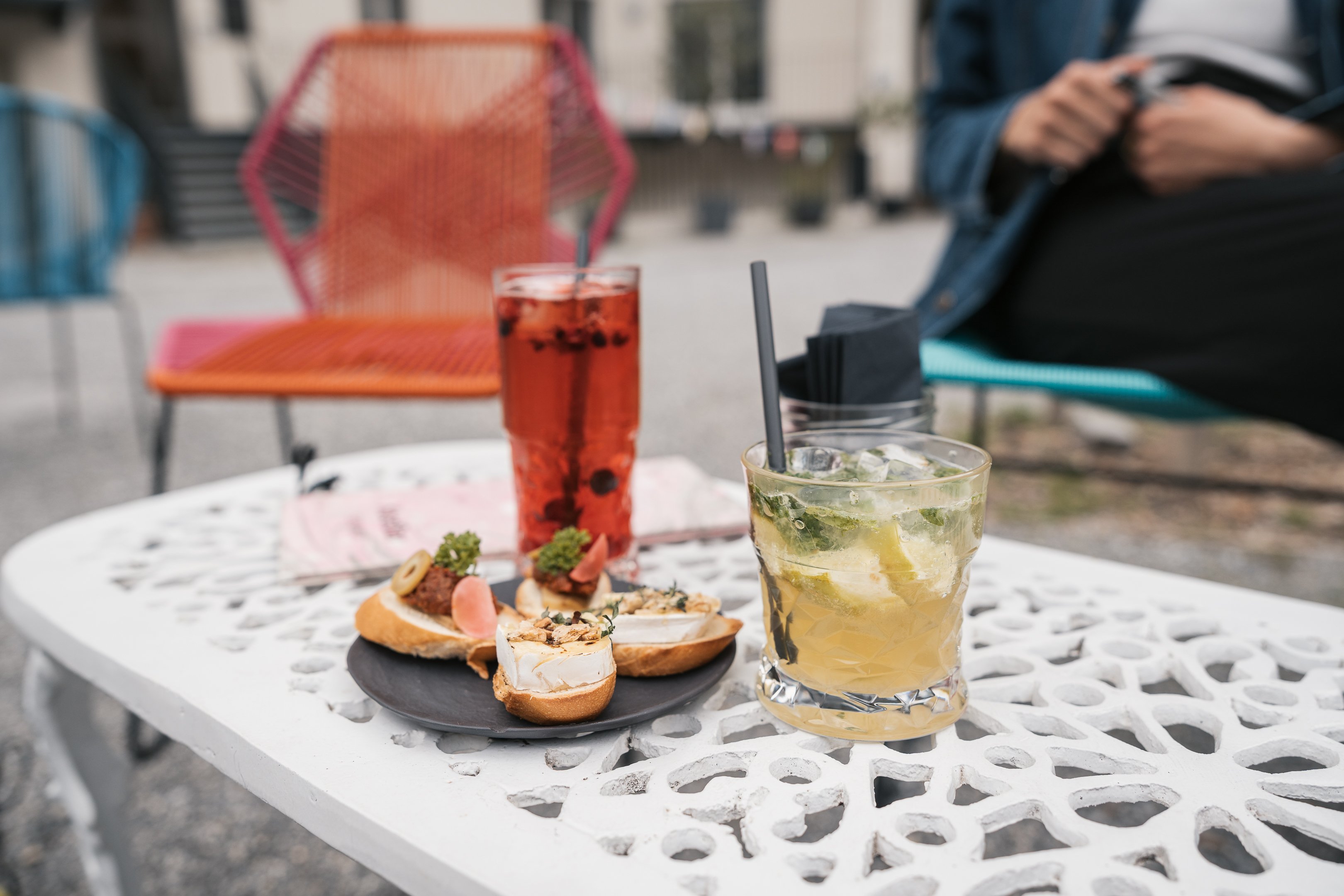 Tisch mit zwei Drinks und vier belegten Brötchen.