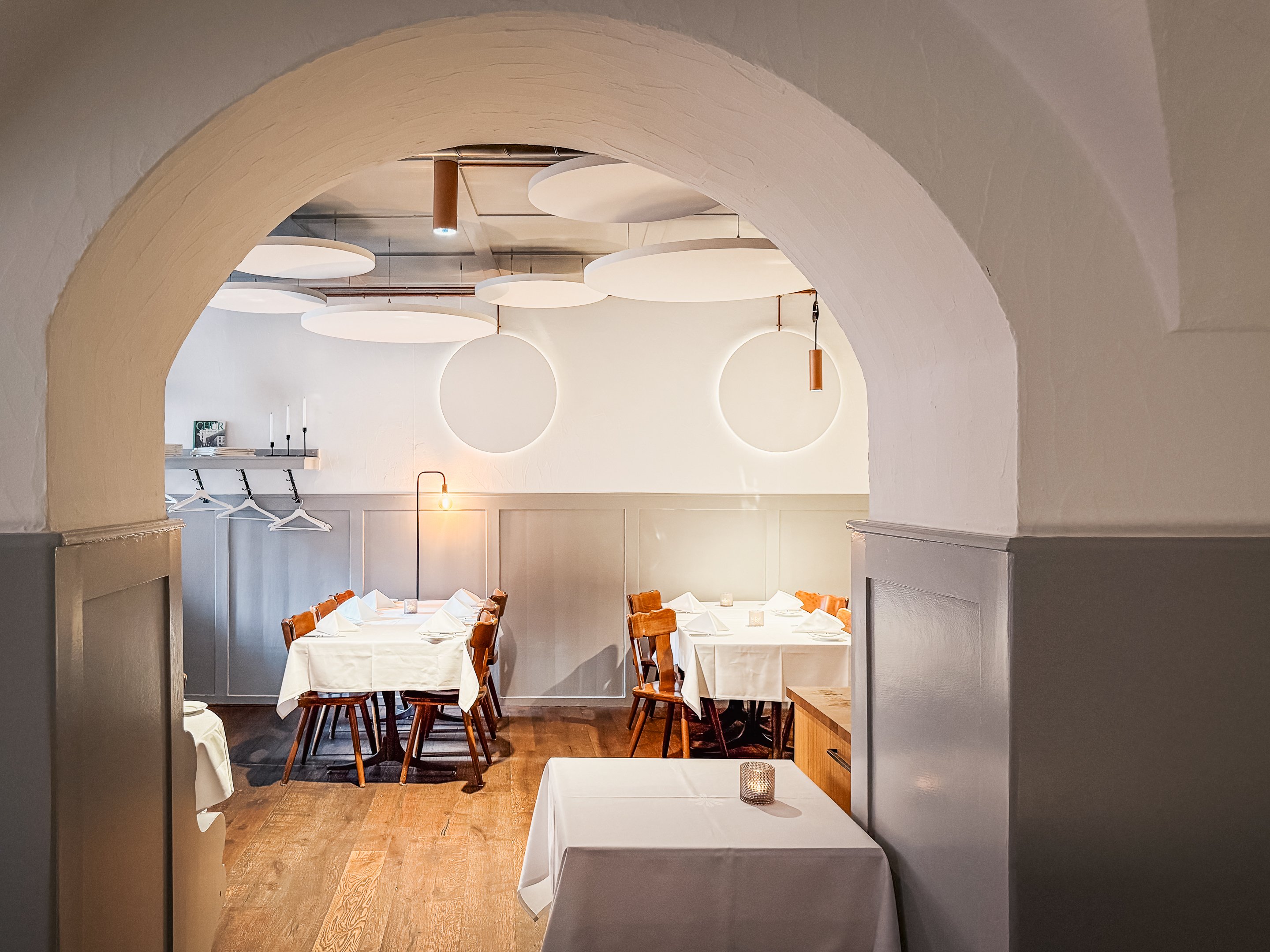 Interieur des Restaurants Brasserie Süsswinkel: Zu sehen sind zwei gedeckte Tische und moderne Leuchten an der Wand.
