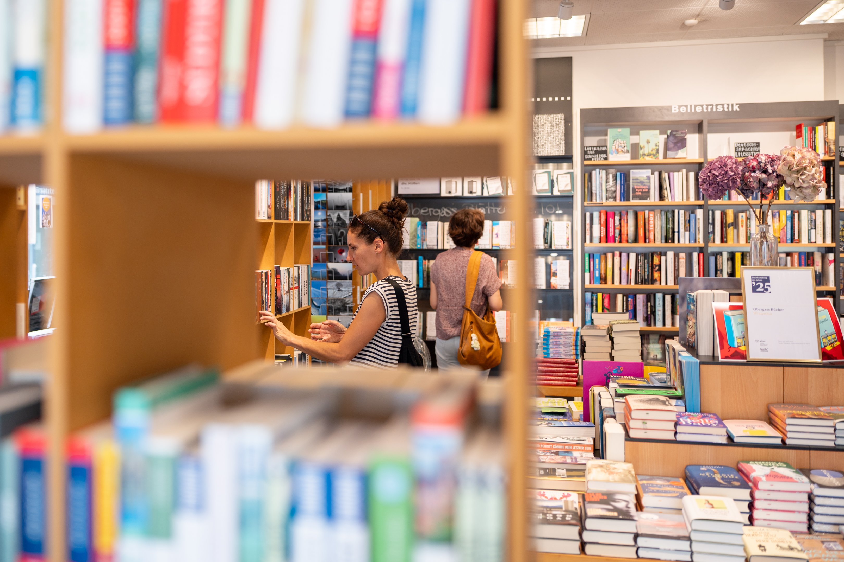 Zwei Frauen stöbern durch die Regale im Bücherladen.