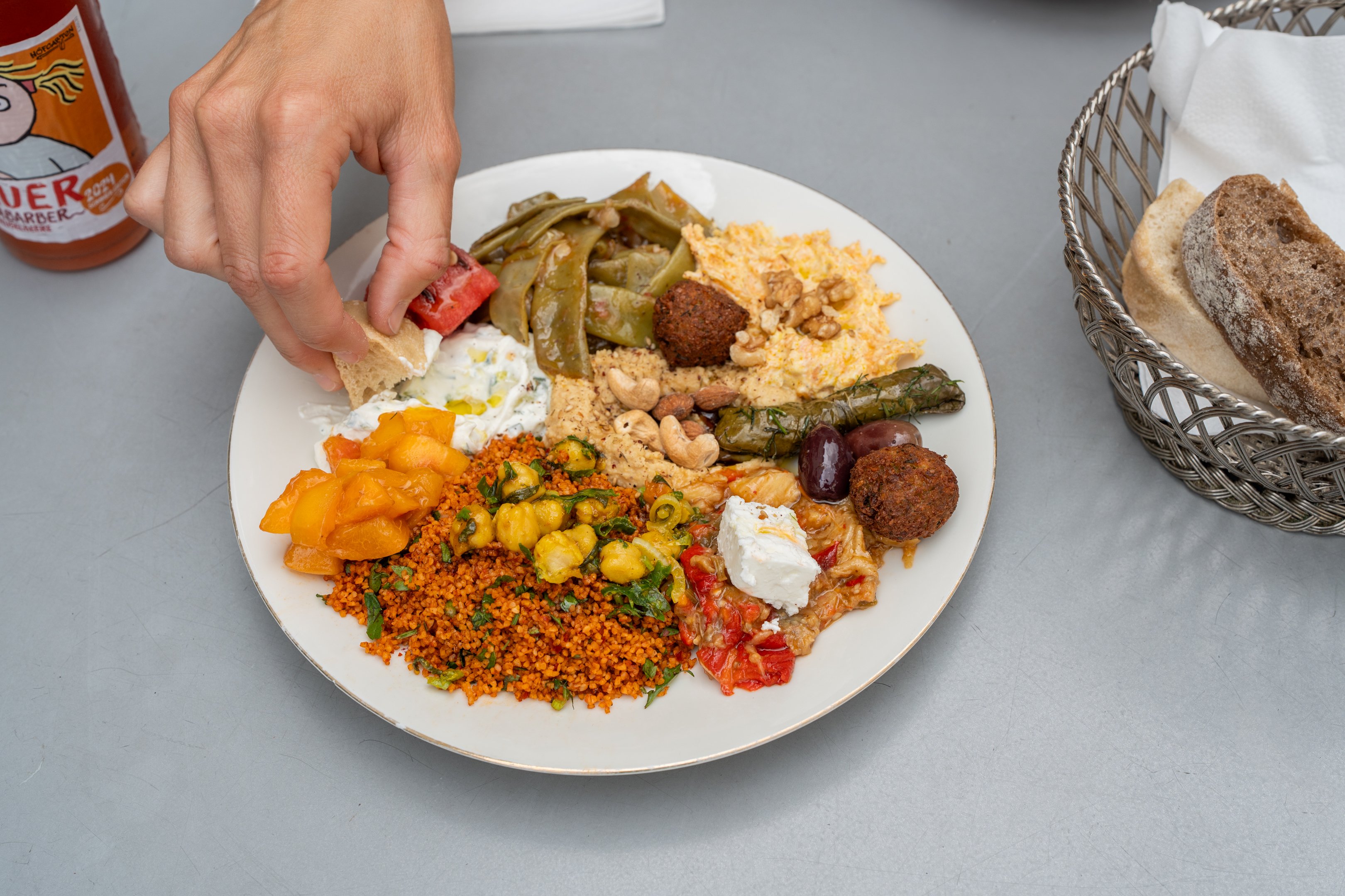 Gemischte Mezze-Platte. Hand dipt Brot in weisse Sauce.