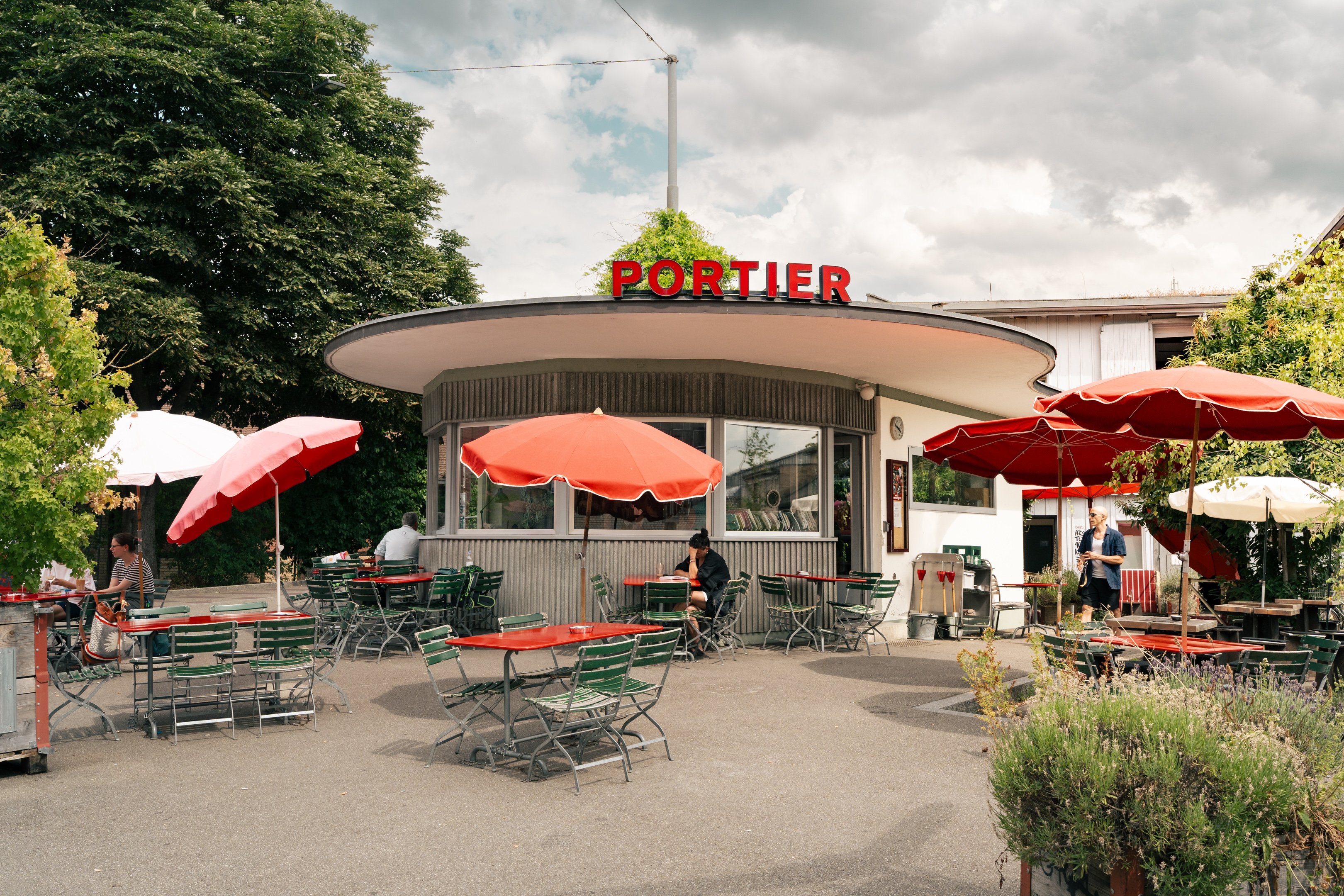Rundes Haus mit bestuhlter Terrasse im Vordergrund.