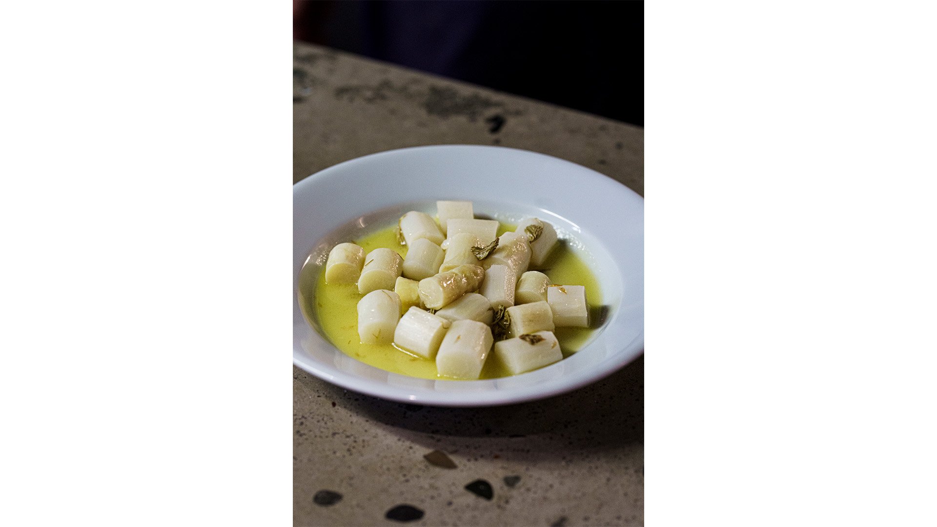 Une assiette blanche avec un plat du restaurant Heisswein (des asperges blanches à l’huile d’olive).