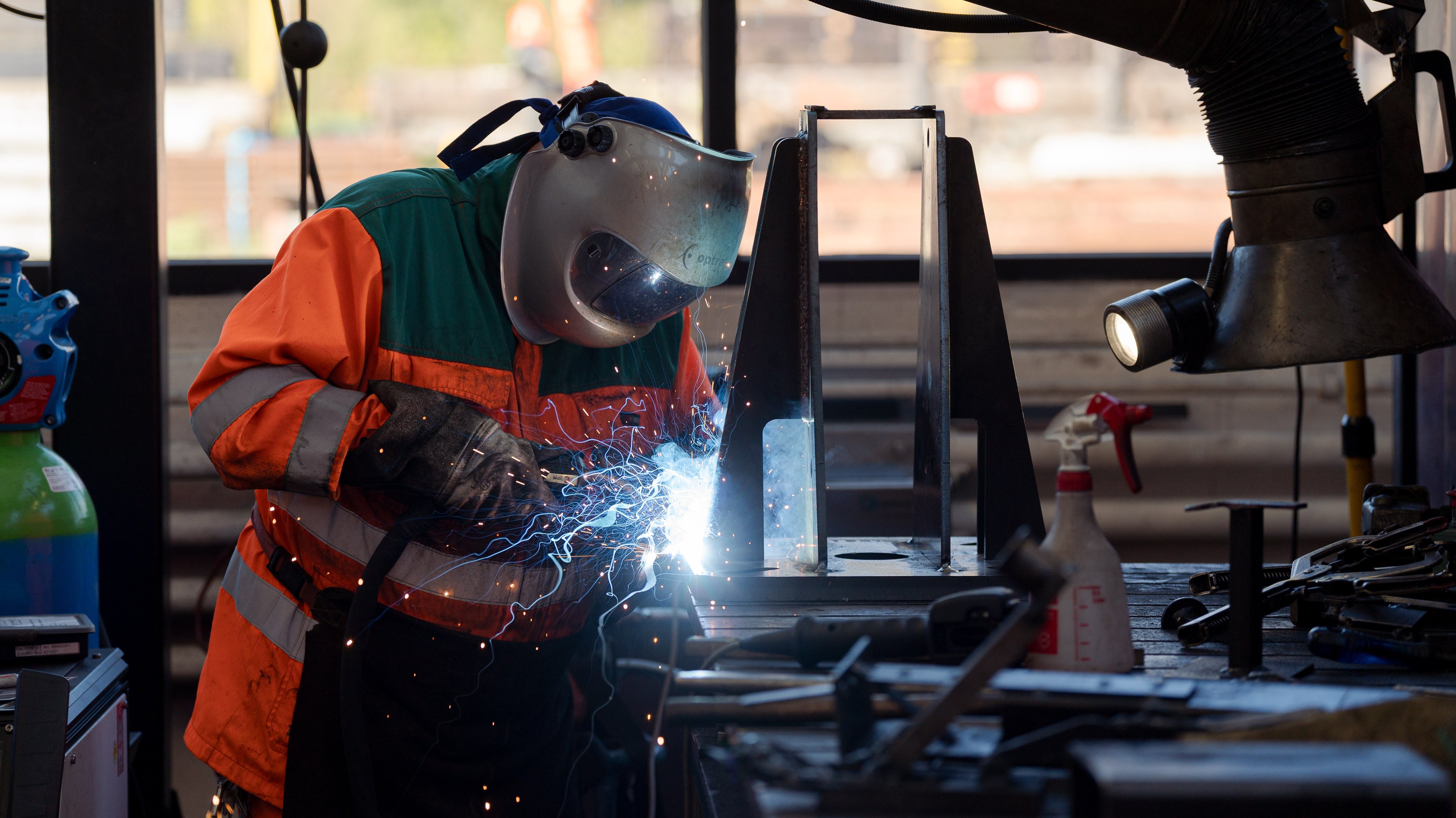 Ein Mitarbeiter schweisst ein Metallstück auf einer Werkbank.