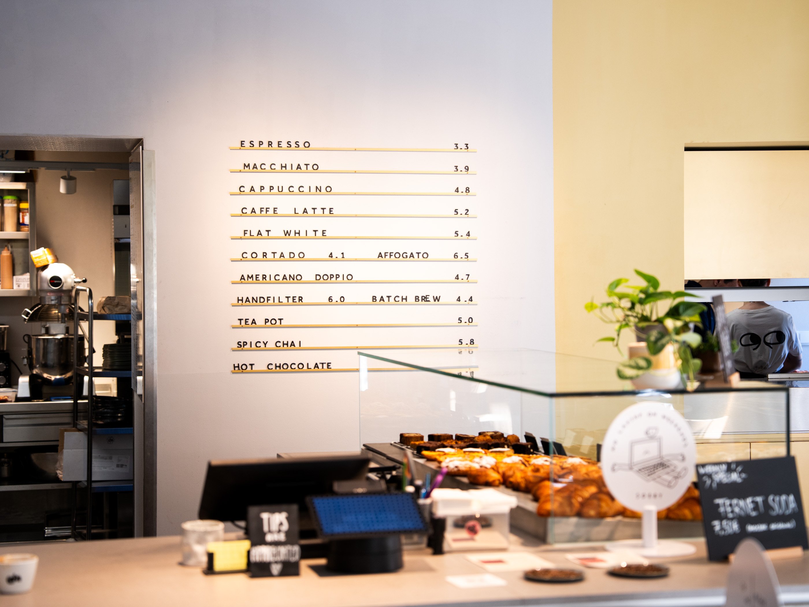 L’intérieur minimaliste du goldener papagei à Vienne, avec la carte des cafés de spécialité indiquée sur le mur.