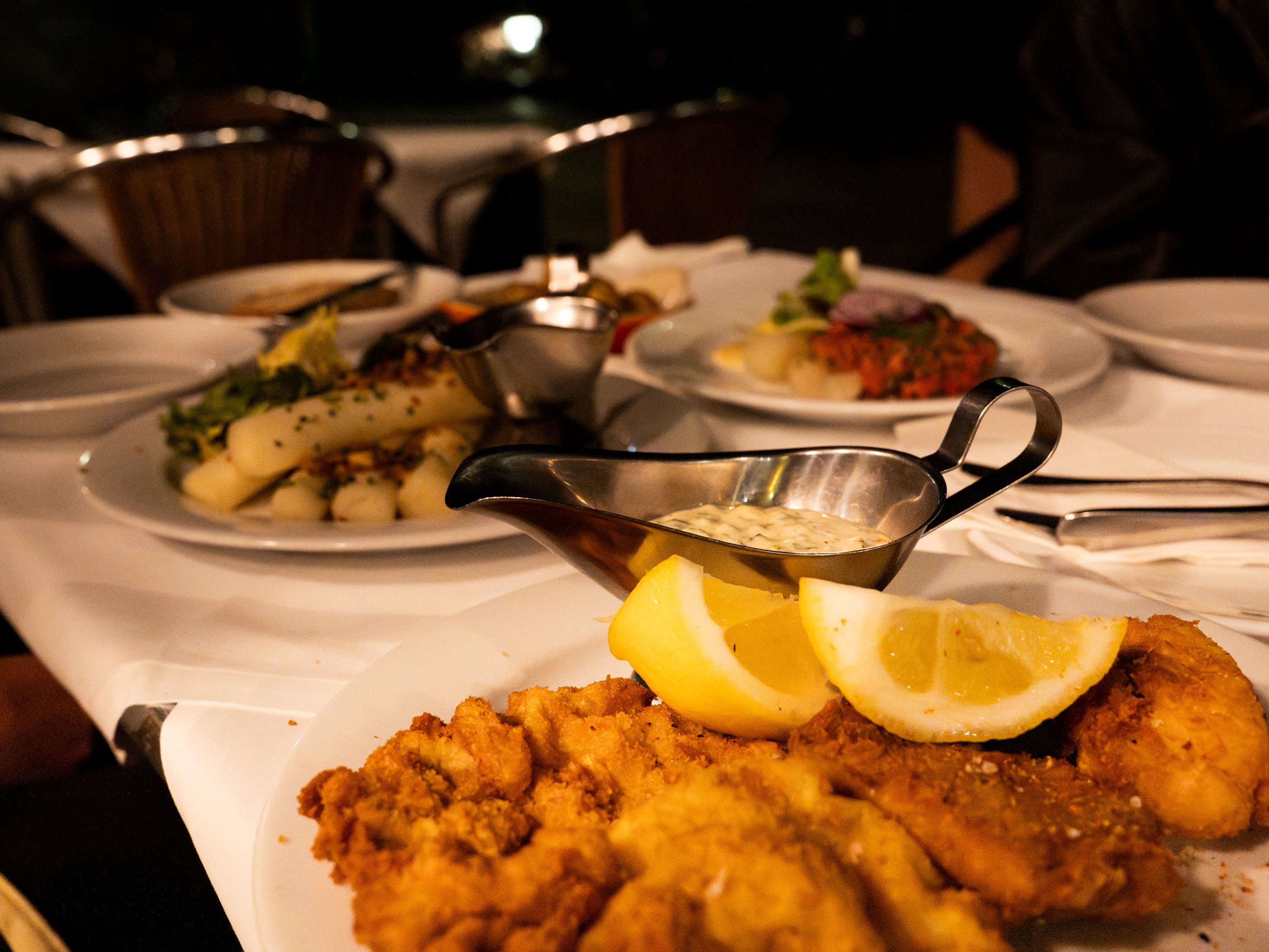 Une escalope viennoise avec des quartiers de citron et une saucière sur une table dressée dans le restaurant Salzamt à Vienne.