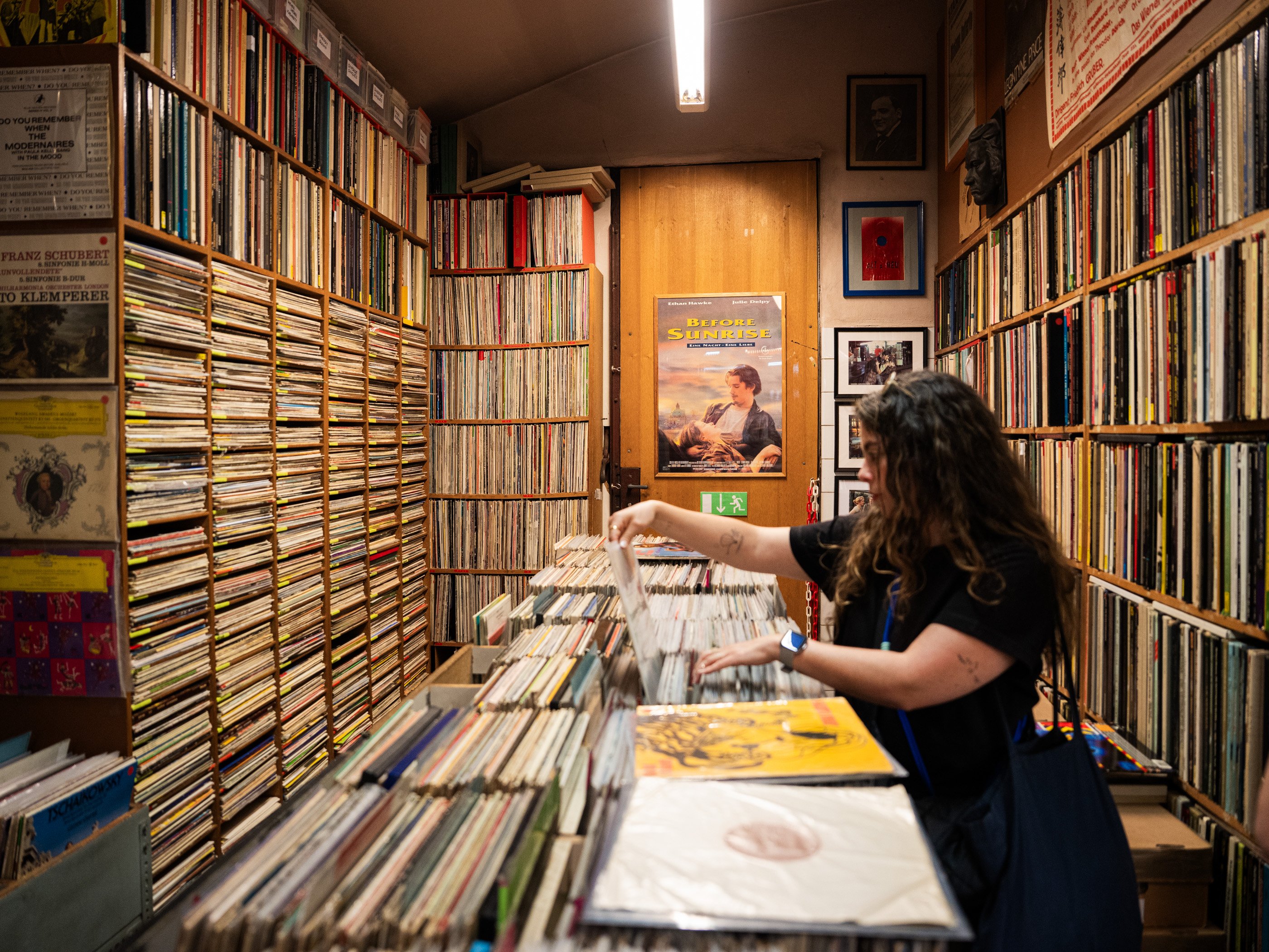Une femme explore la sélection d’albums du disquaire viennois Alt & Neu aux étagères remplies de CD et de vinyles jusqu’au plafond.