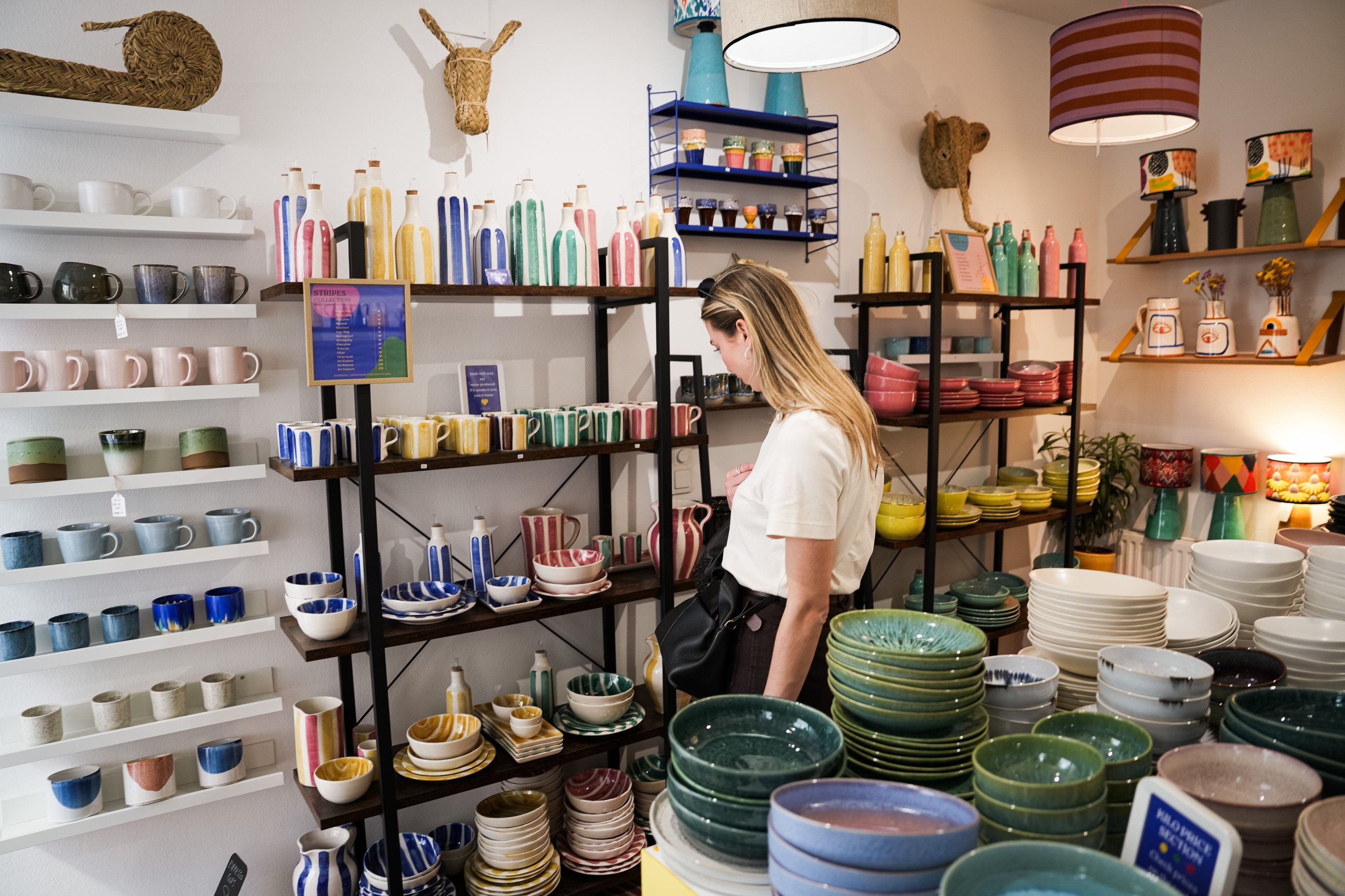 Une femme examine des bols, tasses et vases en céramique chez Singulär, une boutique viennoise qui les vend au kilo.