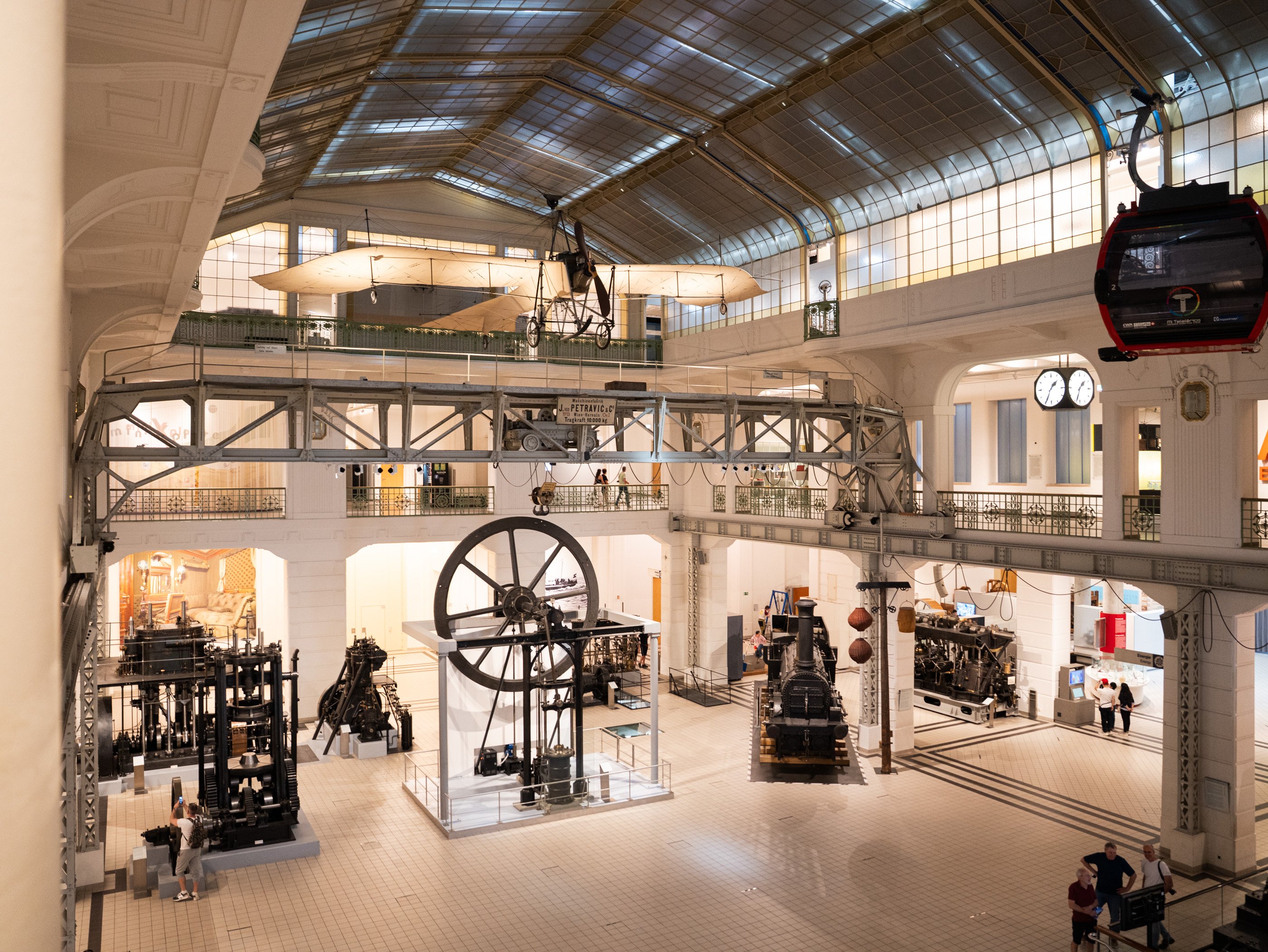 Grand hall d’exposition du Technisches Museum Wien avec des machines historiques, des locomotives et des objets volants.