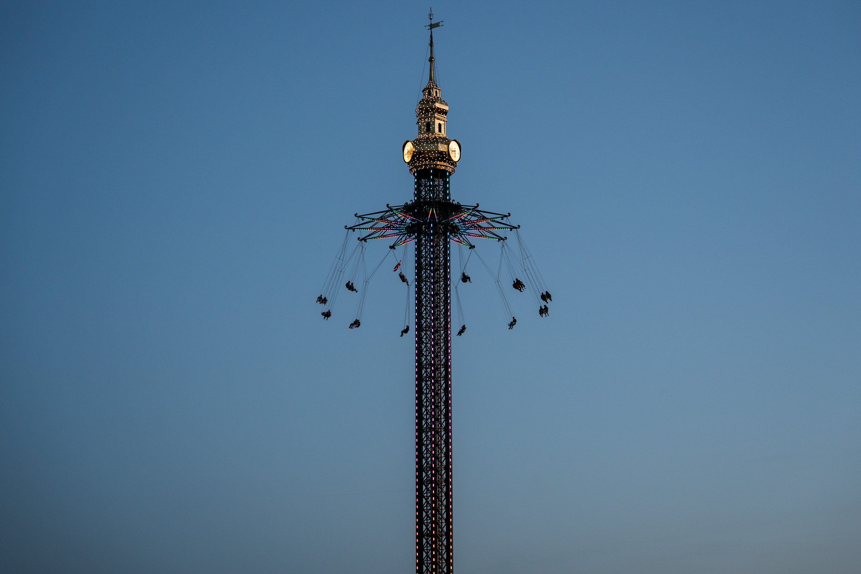 a tour du Prater illuminée avec des chaises volantes en train de tourner devant un ciel crépusculaire.
