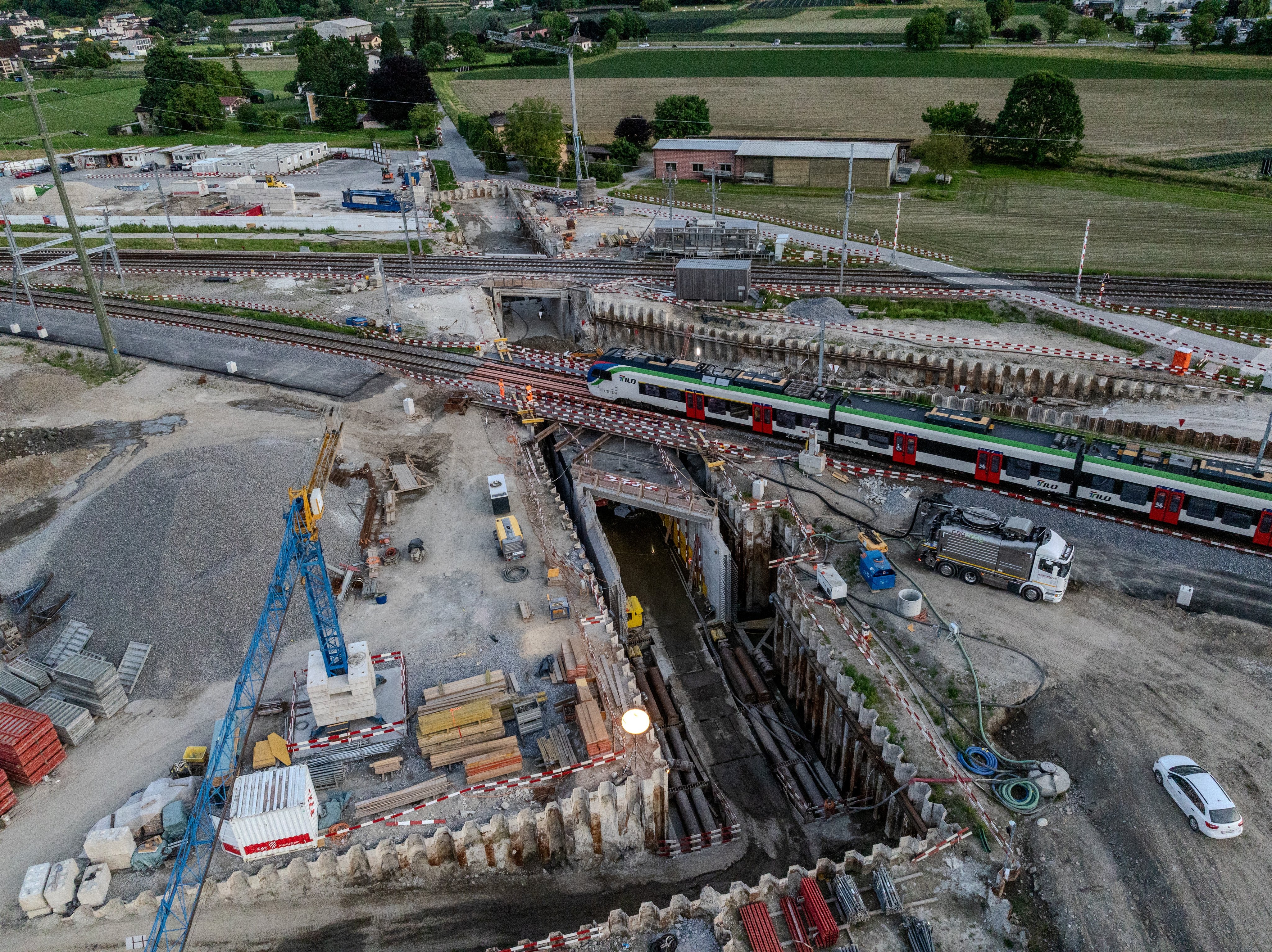 Il passaggio di un treno sulla linea verso Locarno durante la fase di spostamento del monolito sottostante e sullo sfondo la linea verso Luino con il monolito già nella sua posizione finale.