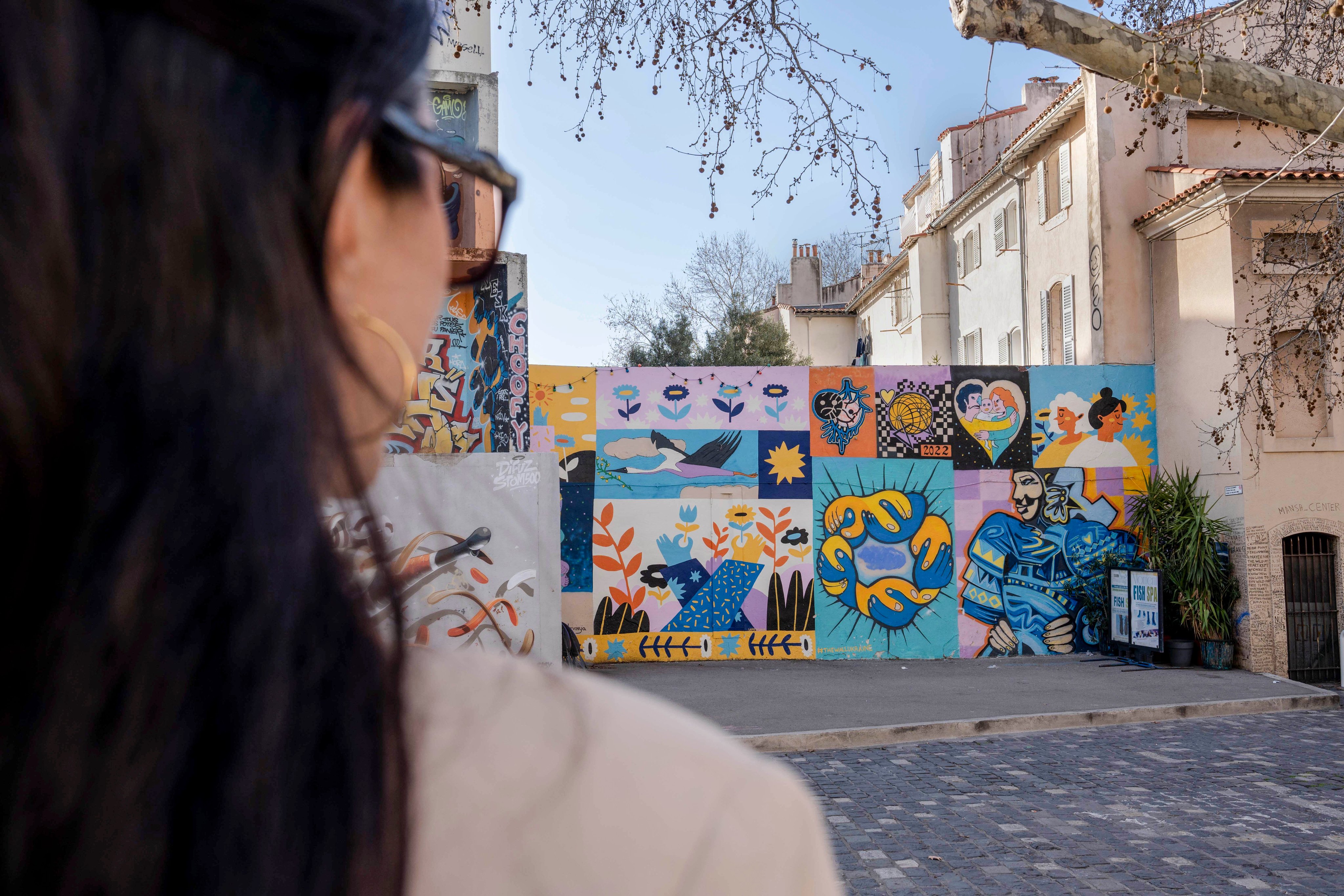 Eine Person betrachtet ein lebendiges Wandgemälde im Le Panier Viertel, ein Zeugnis der lebhaften Kunstszene und der Wertschätzung für urbane Kreativität in Marseille.