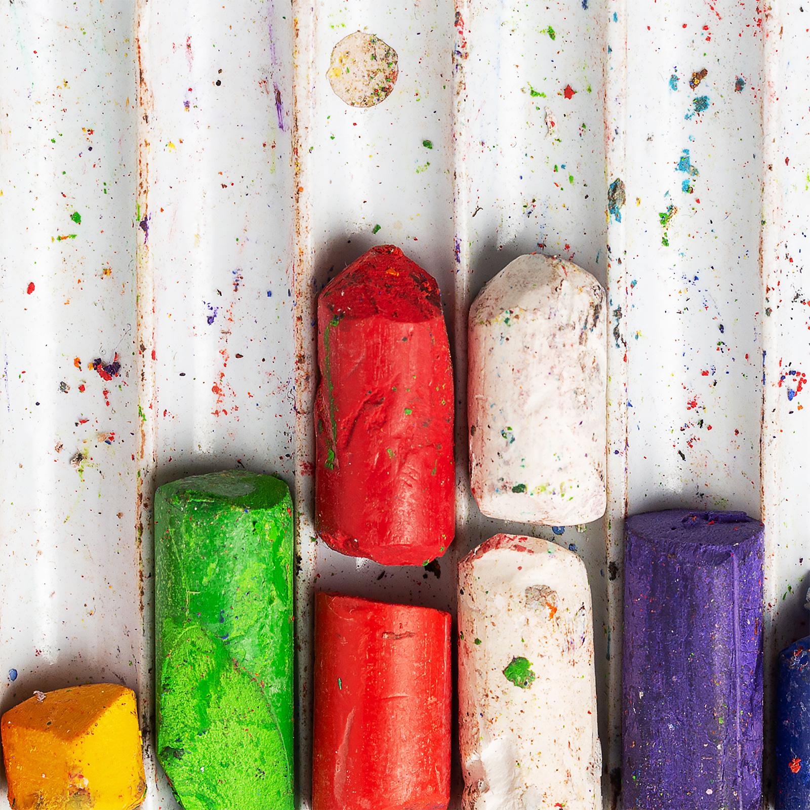 An image of different colors of chalk in a tray.