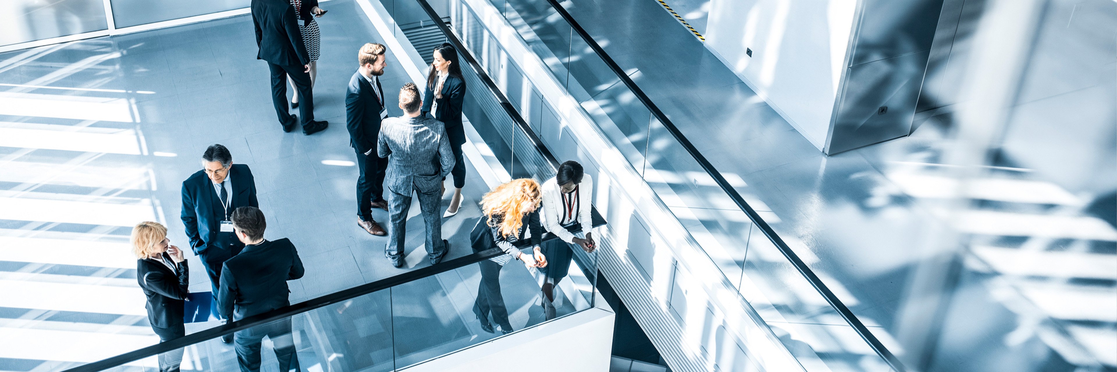 Well-dressed people walking in a busy, high-end office building, suggesting success.