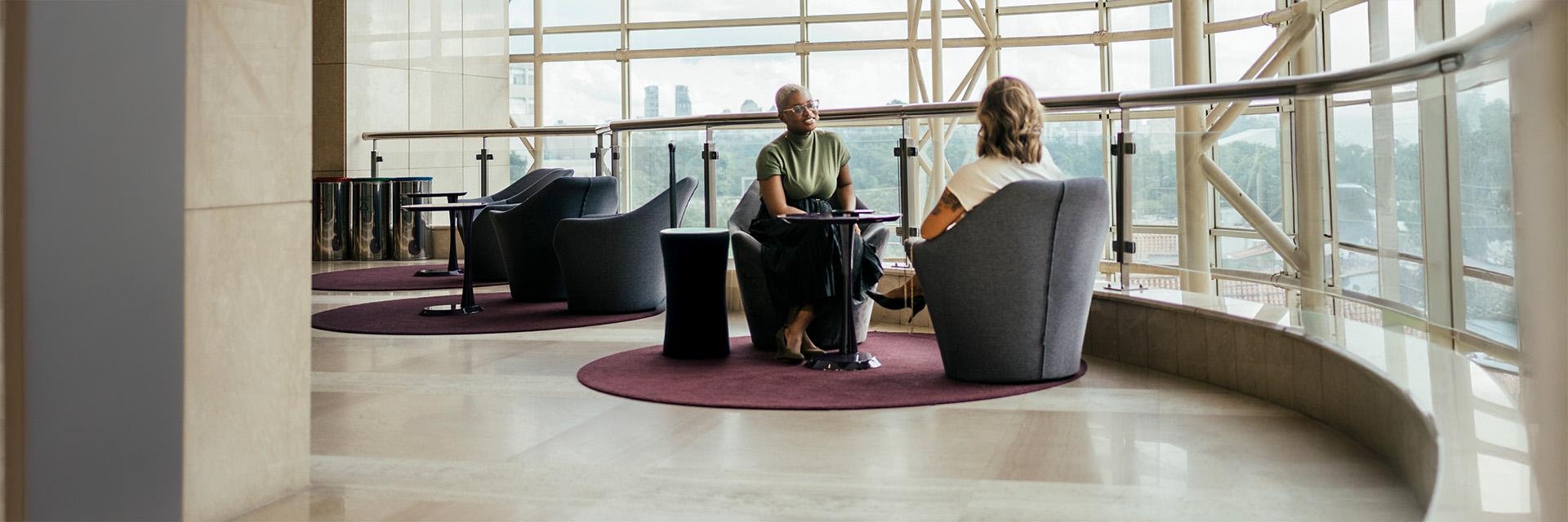 Two people chat in a modern office lounge