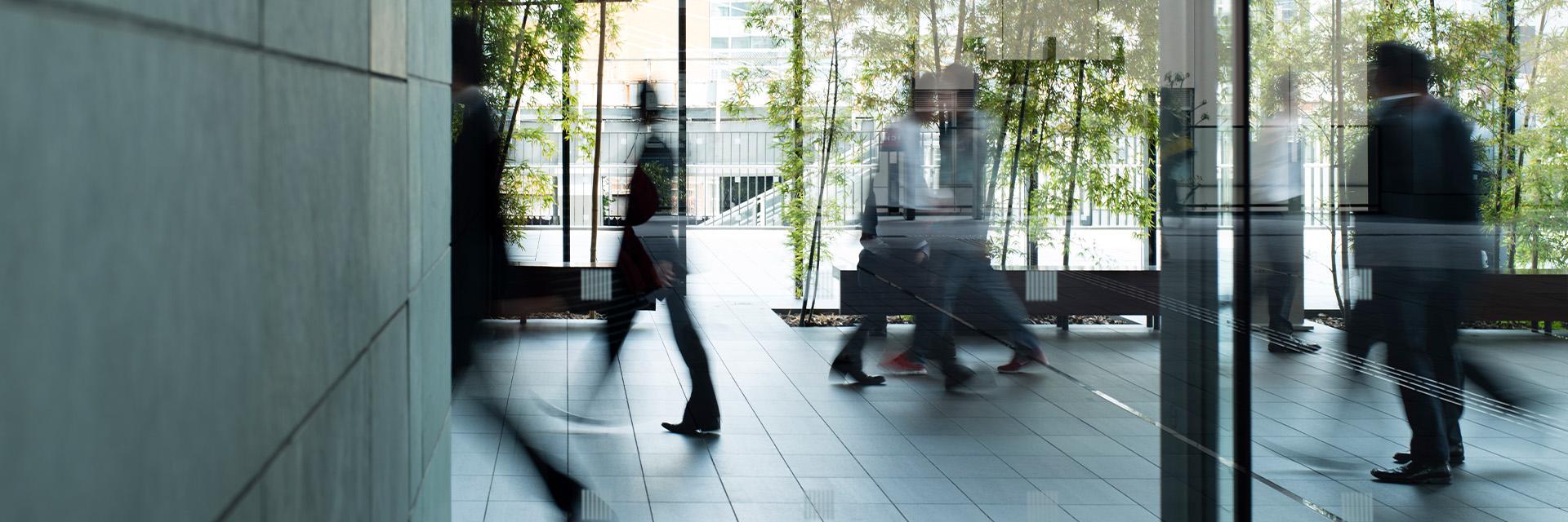 People walk through a lobby with trees