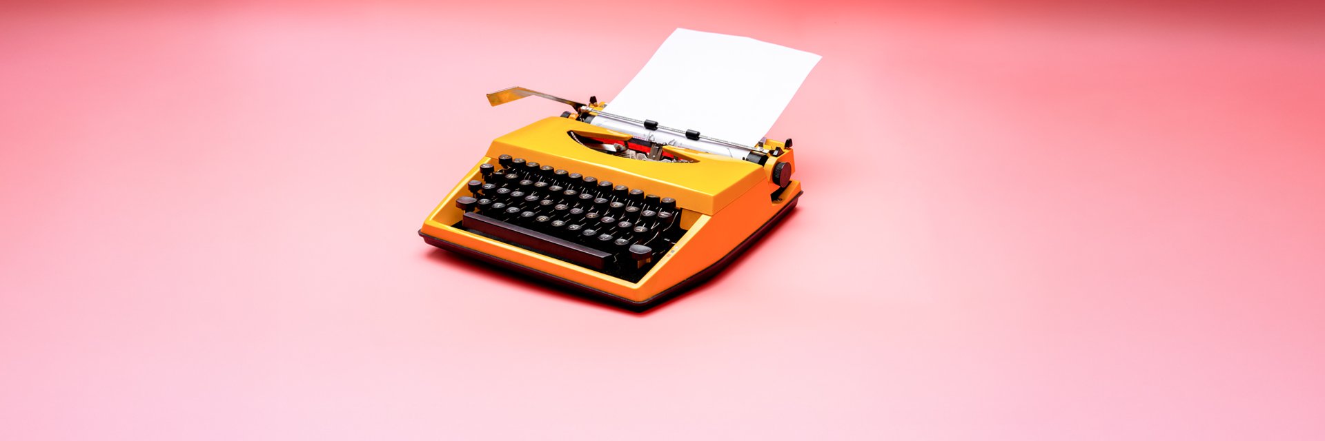 an orange typewriter against a pink background.