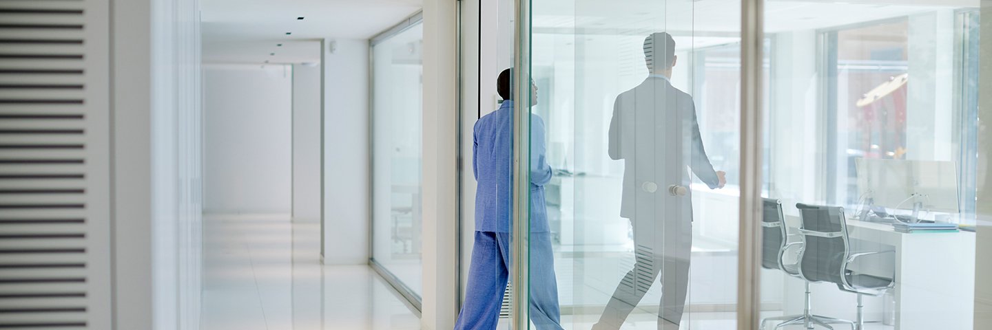 Two people walk through a workspace