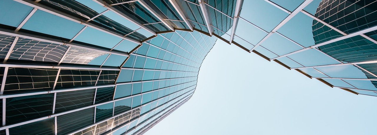 An upwards view of a wave-shaped glass office building