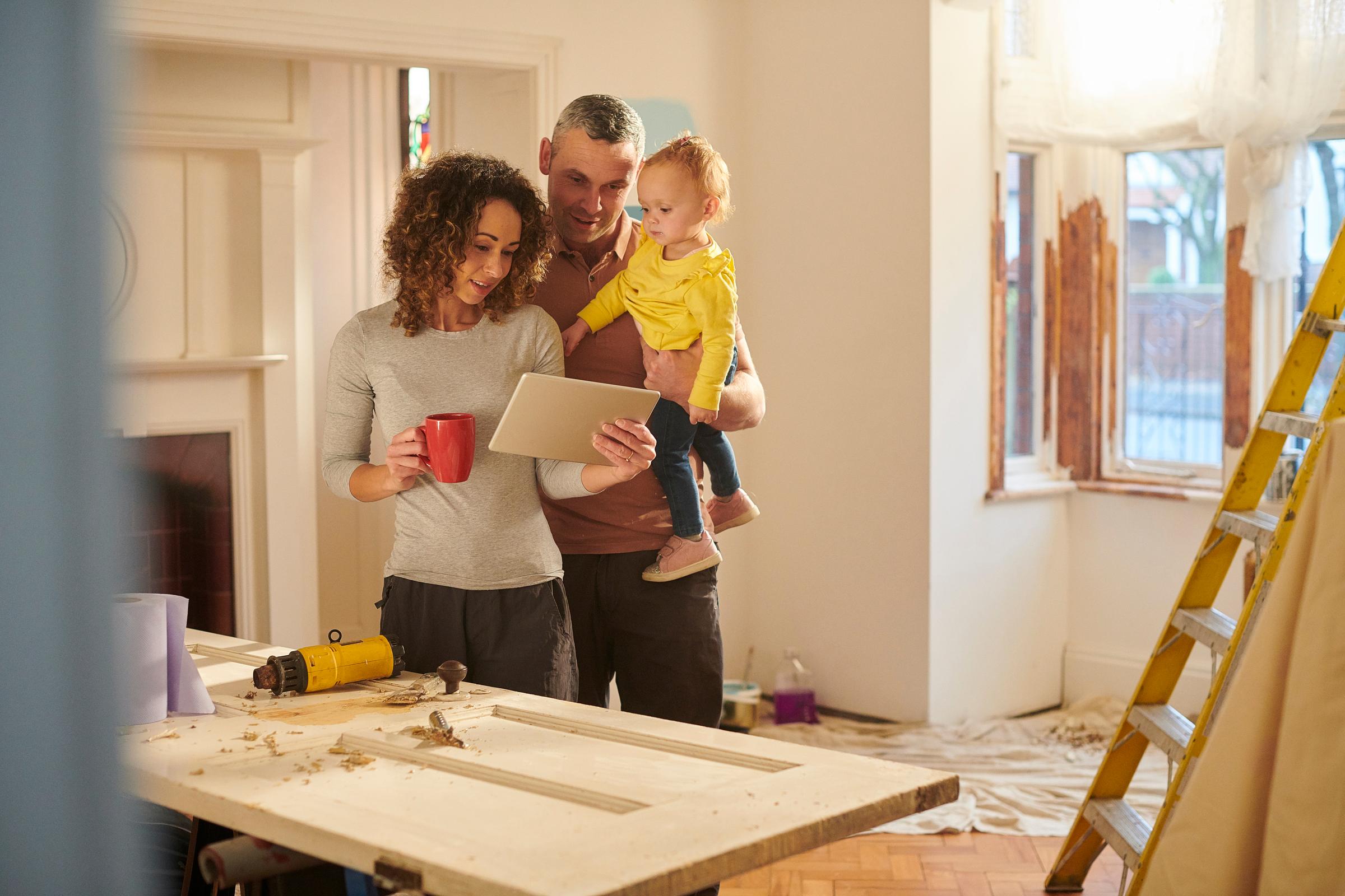 Family checking their home insurance on ipad, surrounded by DIY living room.