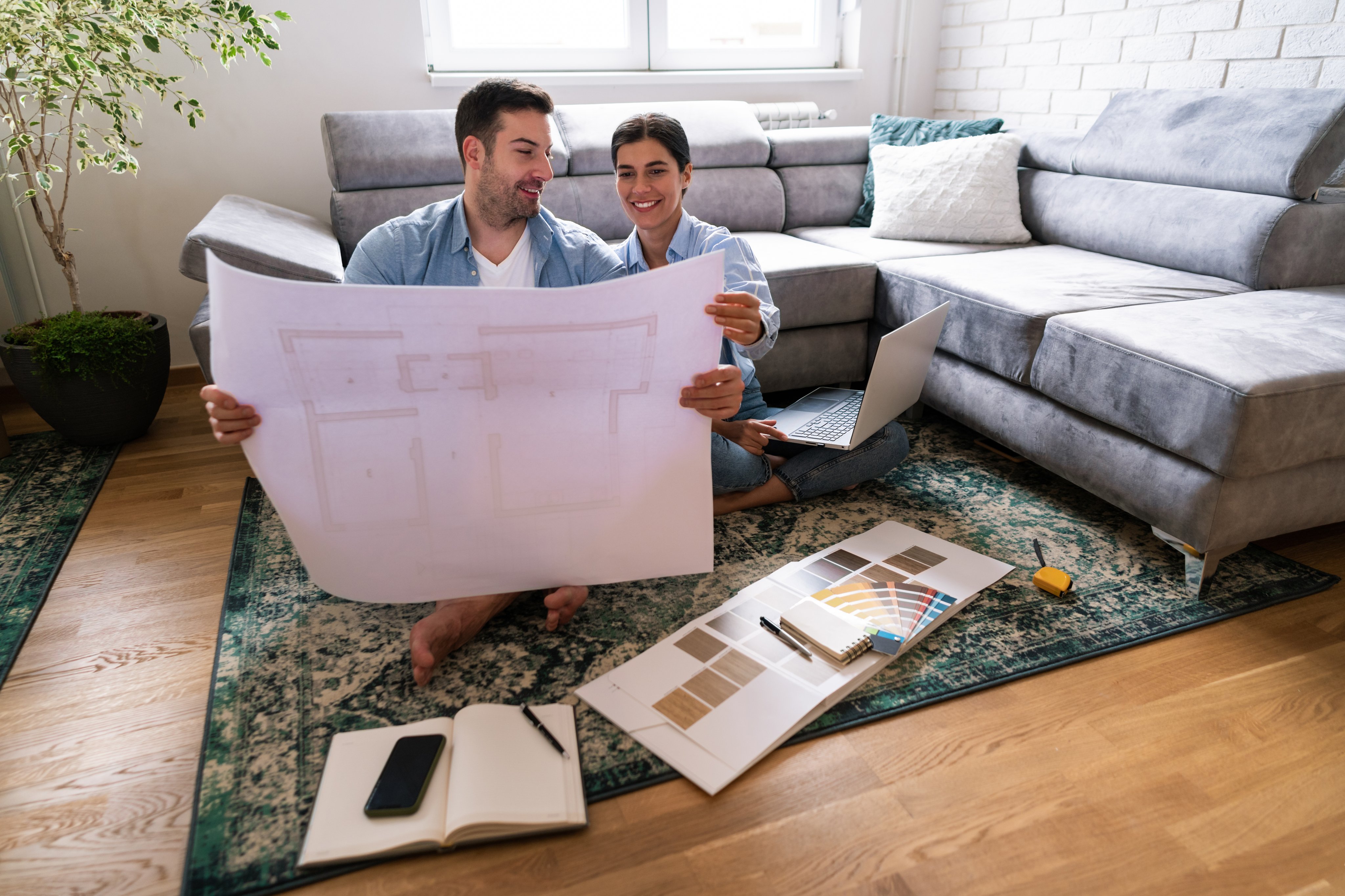 Young couple sitting on the floor looking at the blueprint of their home